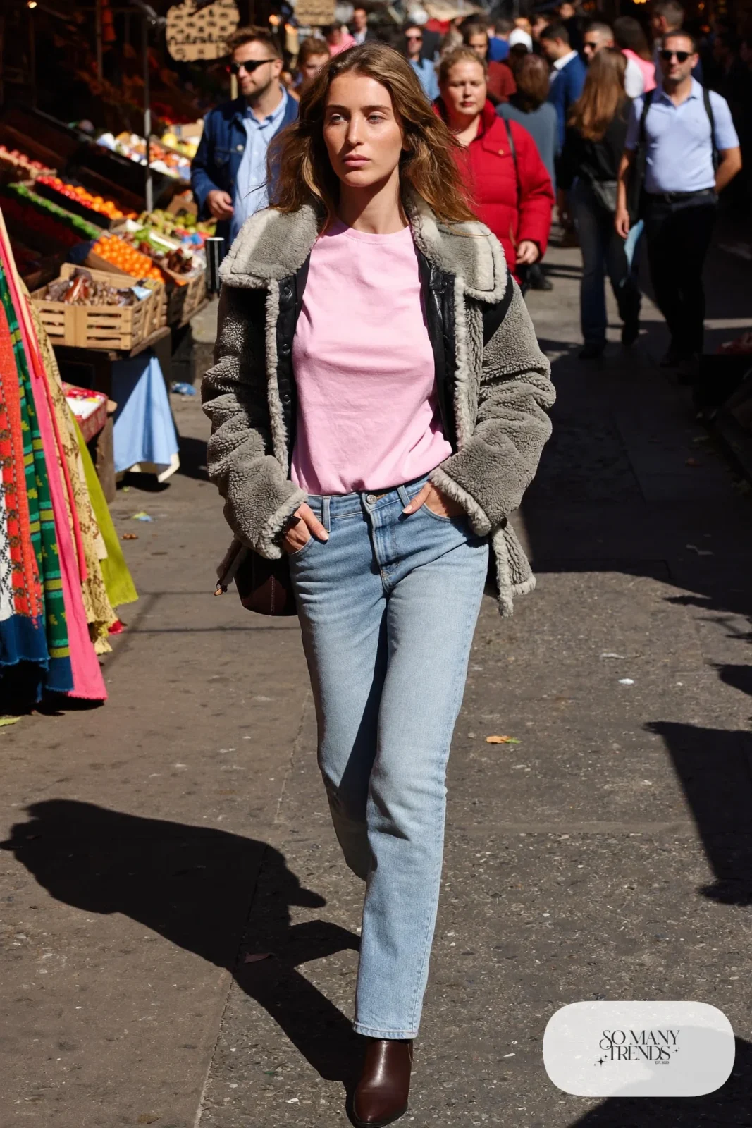 Woman in a gray faux shearling jacket, pink tee, light wash straight jeans and brown boots, outfit 28