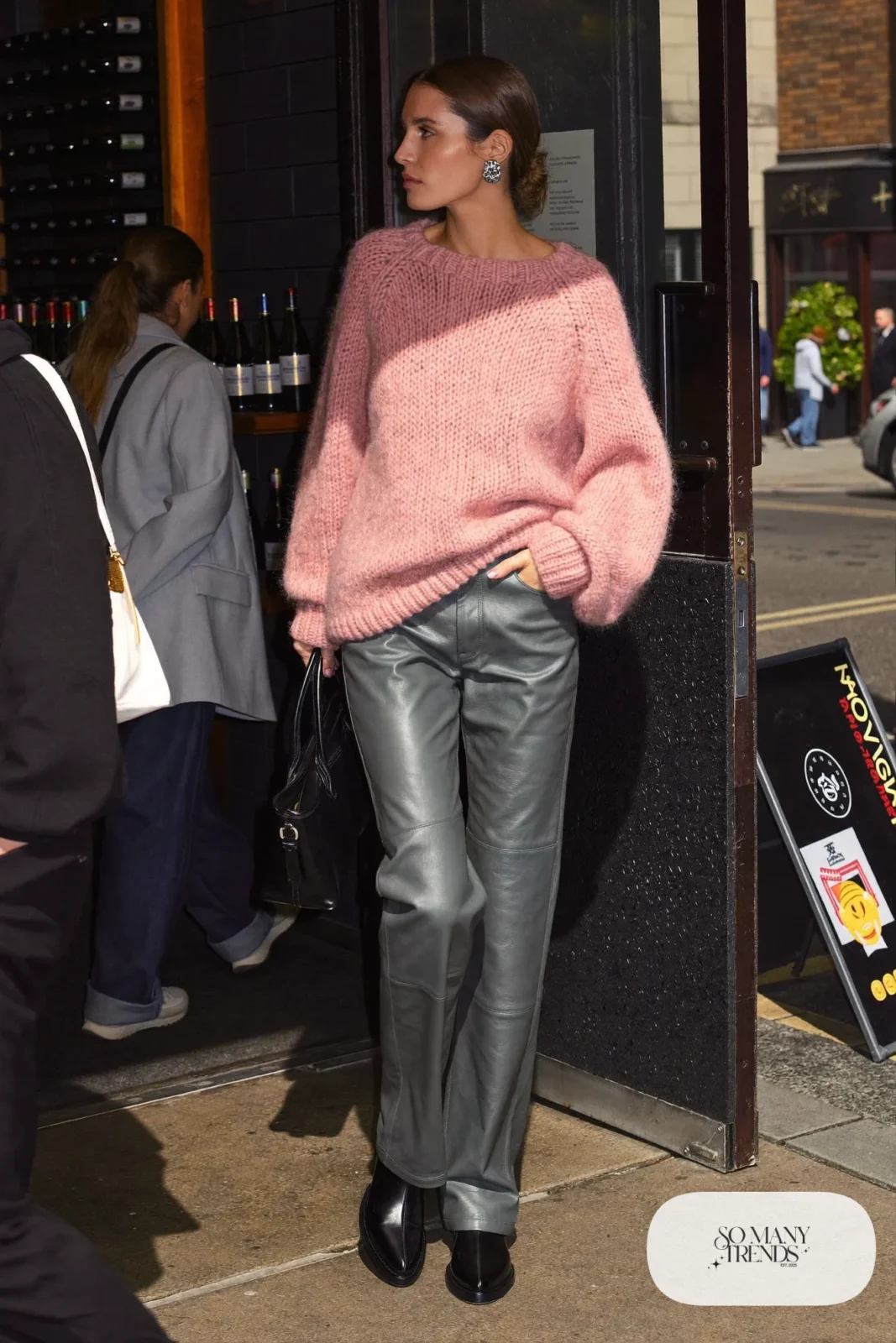 Woman in a pink knit sweater, gray faux leather straight pants, silver jewelry and black boots, outfit 16