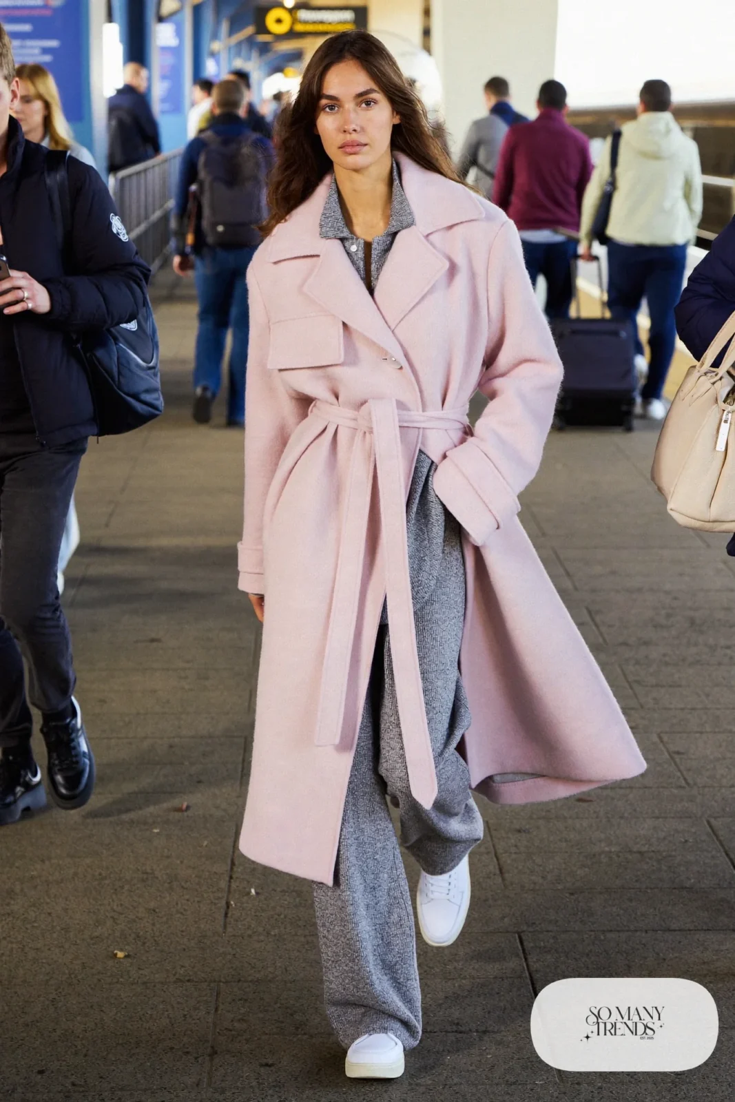 Woman in a pale pink belted wool coat, gray knit top, gray knit pants and white sneakers, outfit 27