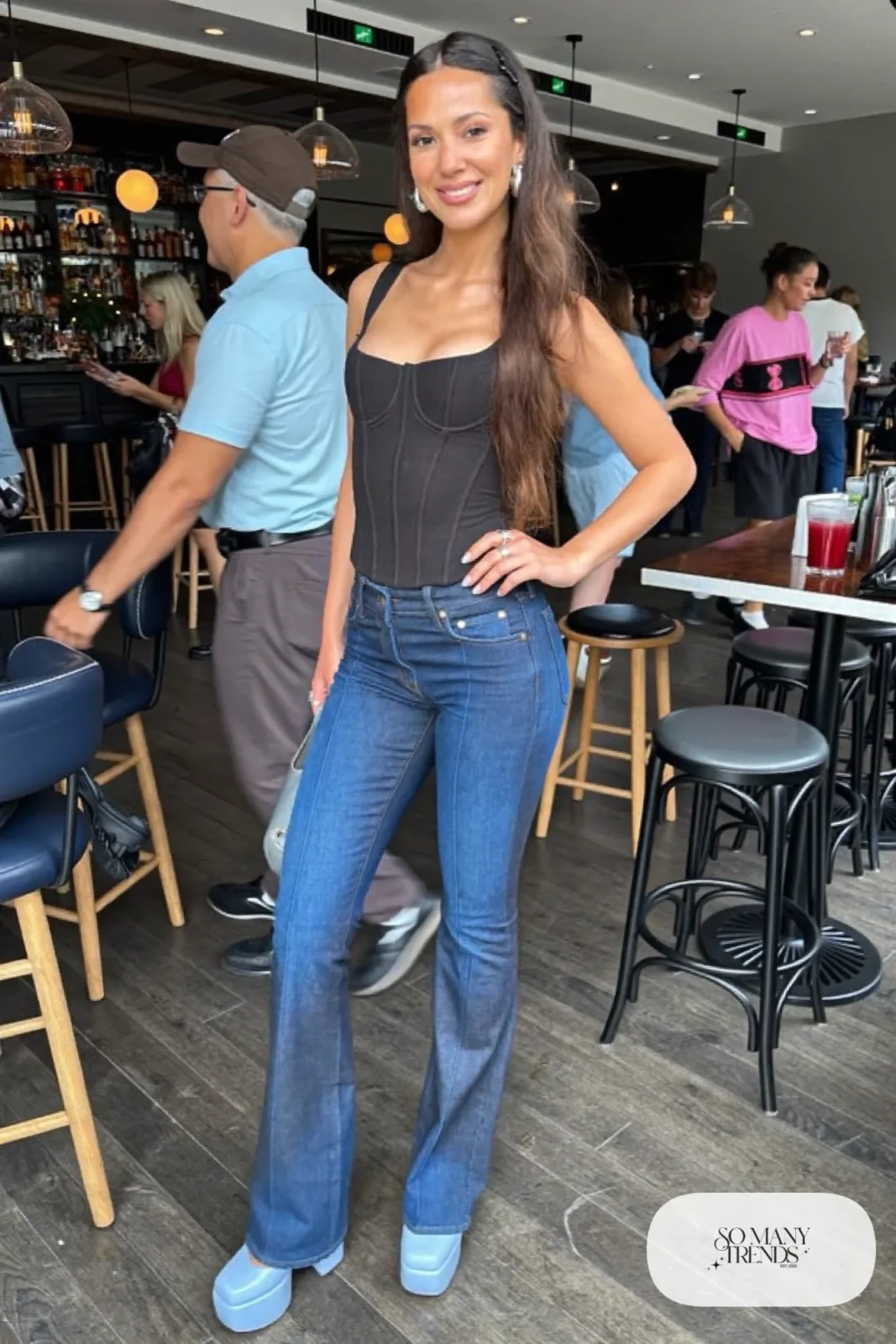 Woman in dark flared jeans, black corset-seamed top and powder blue platform pumps, outfit 11
