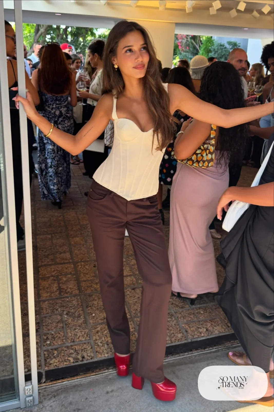 Woman in chocolate straight pants, cream corset-style top and cherry red platform pumps, outfit 20