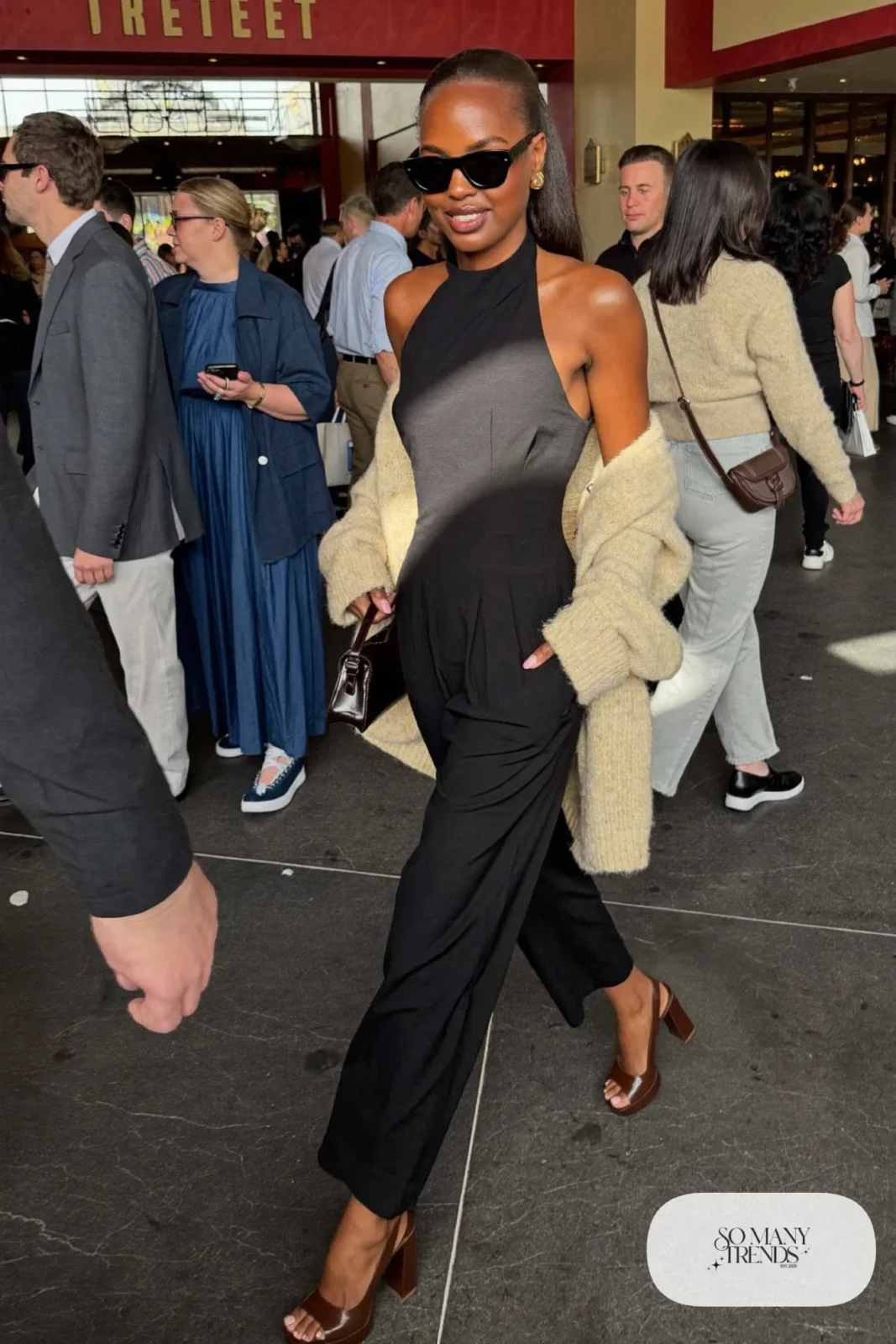 Woman in a black halter jumpsuit, cream cardigan and chocolate platform pumps, outfit 23