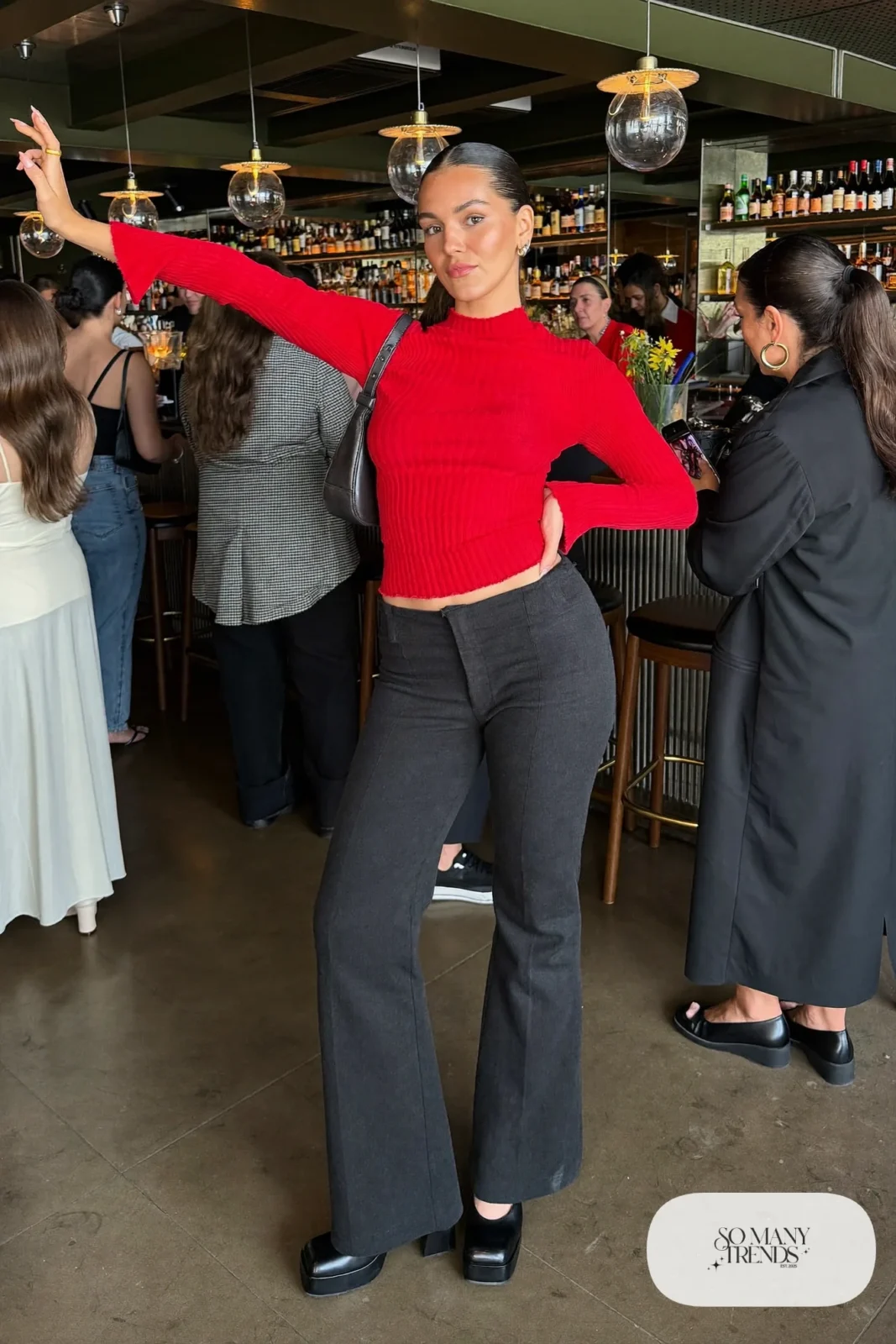 Woman in charcoal flared pants, cherry red fitted knit top and black platform pumps, outfit 24