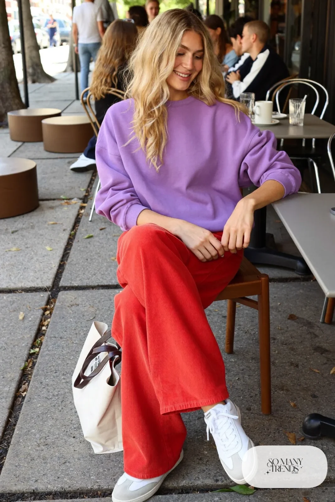 Woman in an oversized lilac sweatshirt, red corduroy straight pants and white sneakers, look 10