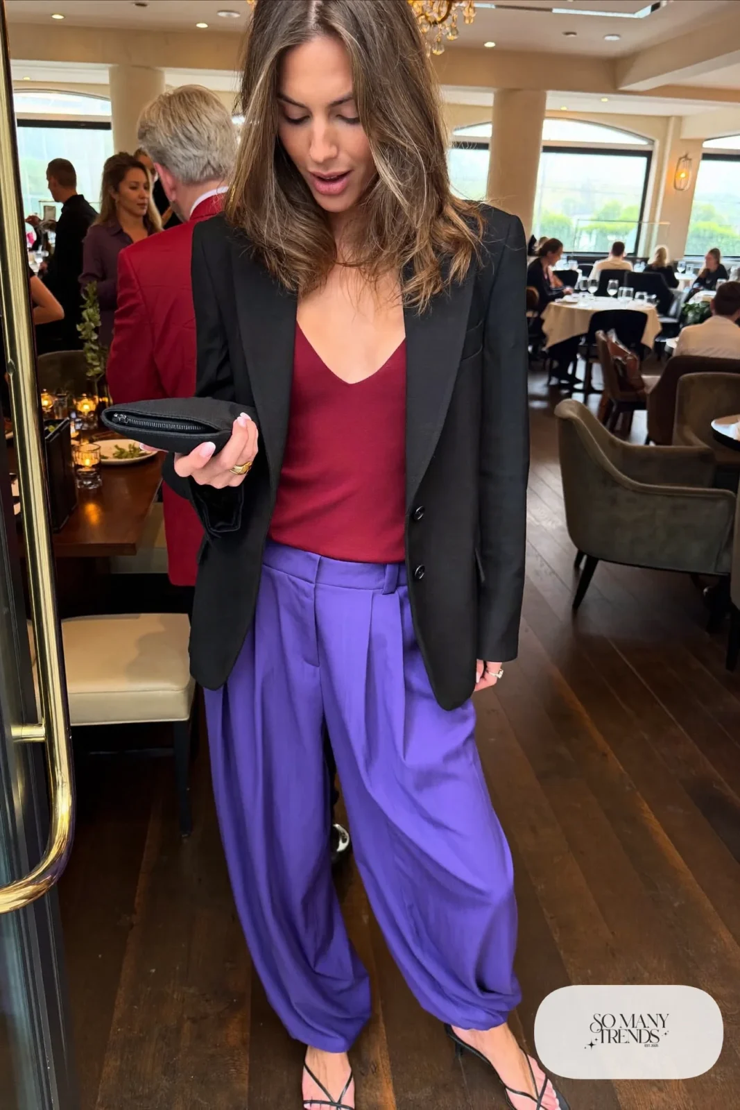 Woman in a wine red camisole, violet wide-leg pants, black blazer and black strappy heels, look 11