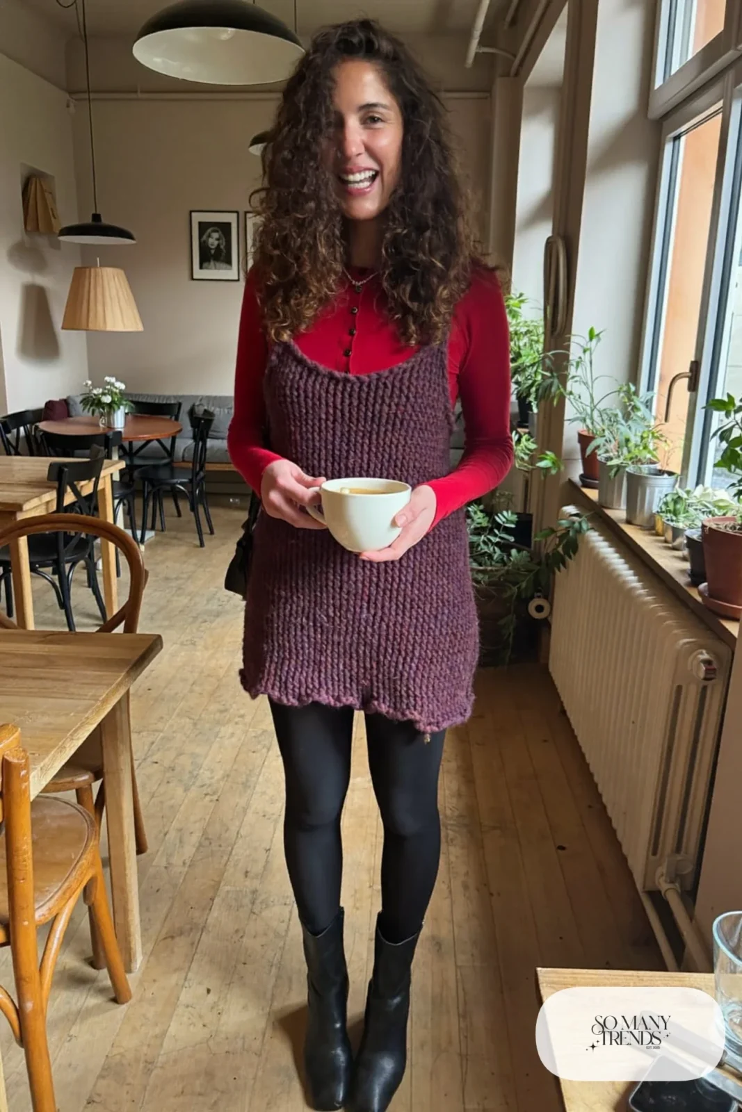 Woman in a loose plum knit mini dress layered over a red fitted top, black tights and black ankle boots, look 12