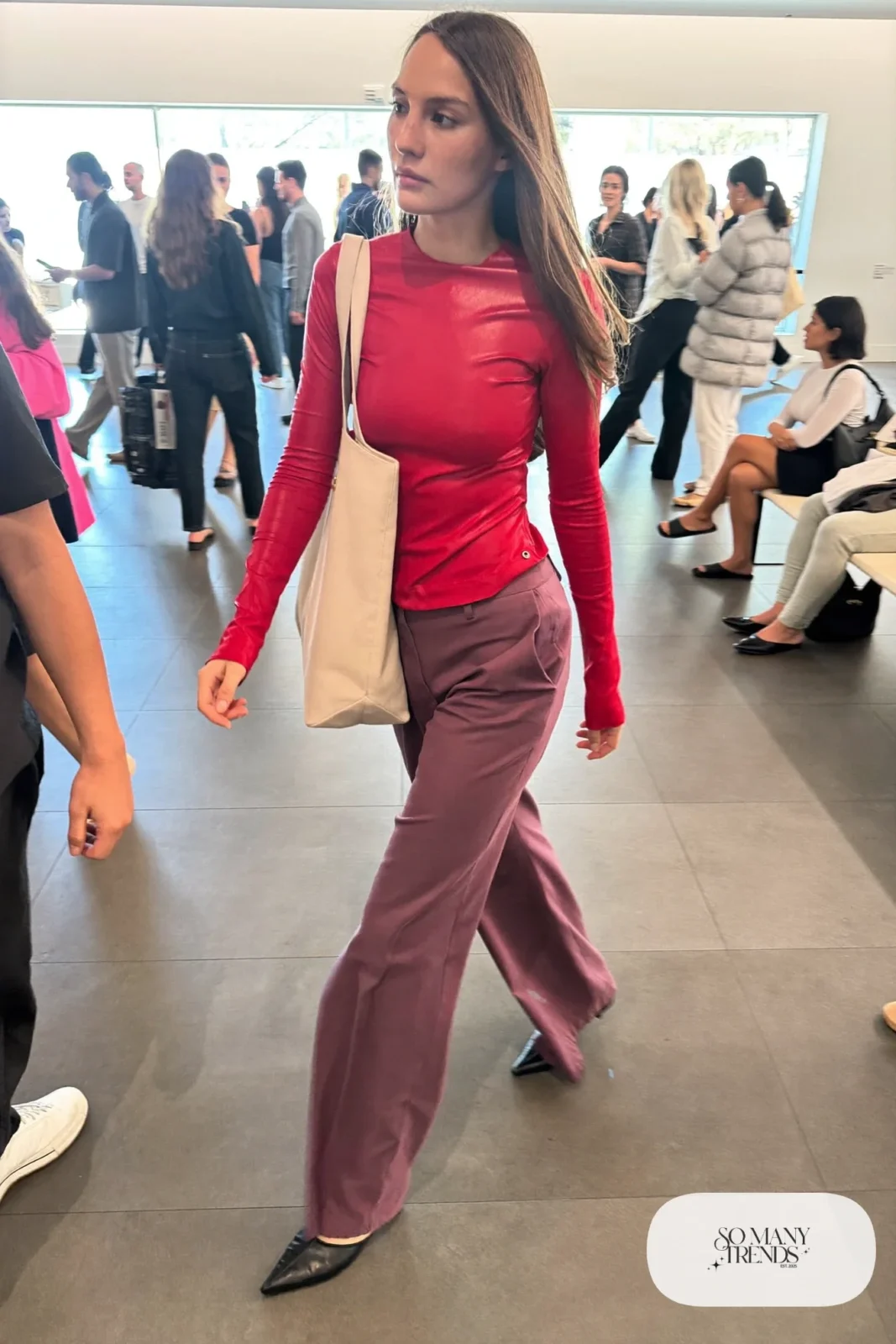 Woman in a cherry red fitted long-sleeve top, plum high-rise wide pants and black pointed mules, look 18