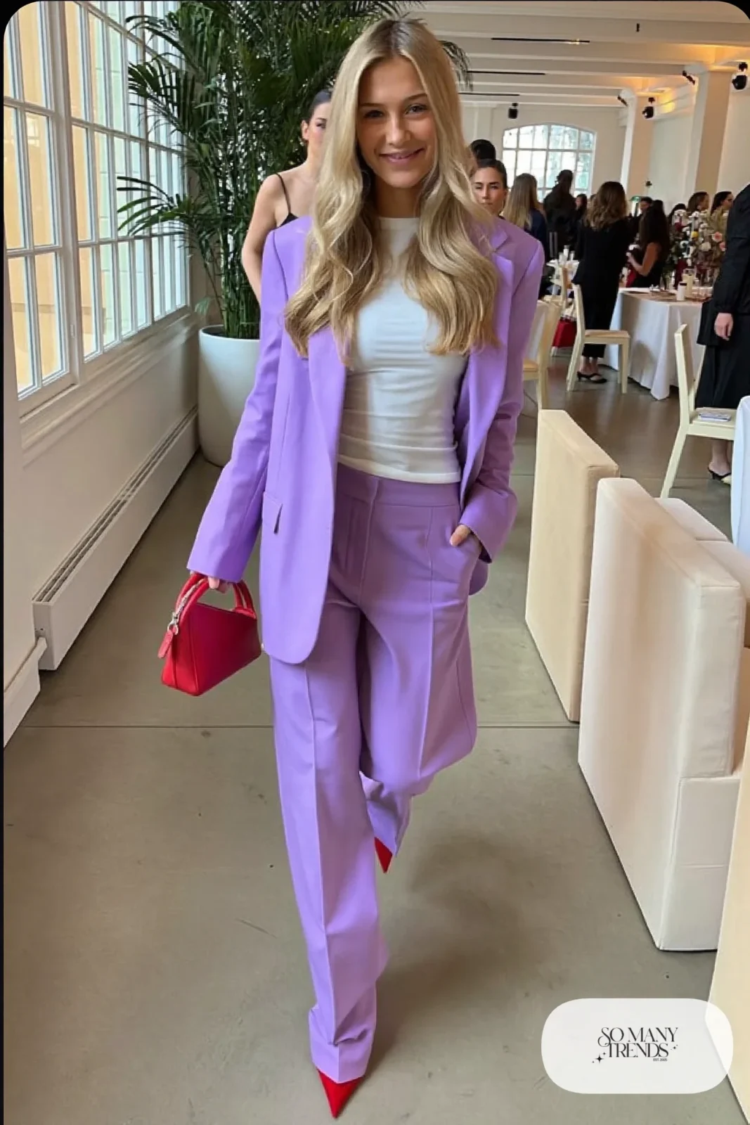 Woman in a lilac blazer and wide pants set with red pointed heels and a red bag, look 20