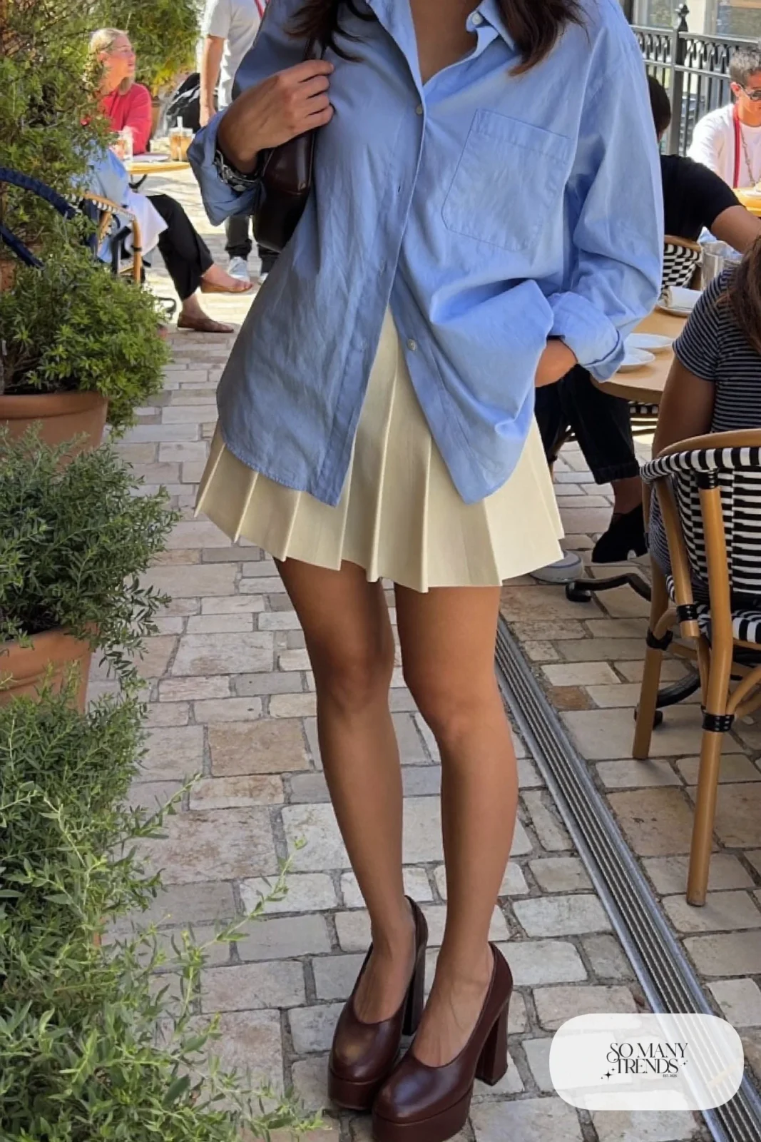 Woman in a cream pleated mini skirt, oversize powder blue shirt and chocolate platform pumps, outfit 13