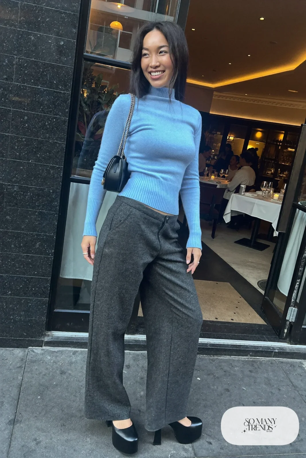 Woman in wide-leg charcoal pants, fitted powder blue sweater and black platform pumps, outfit 19