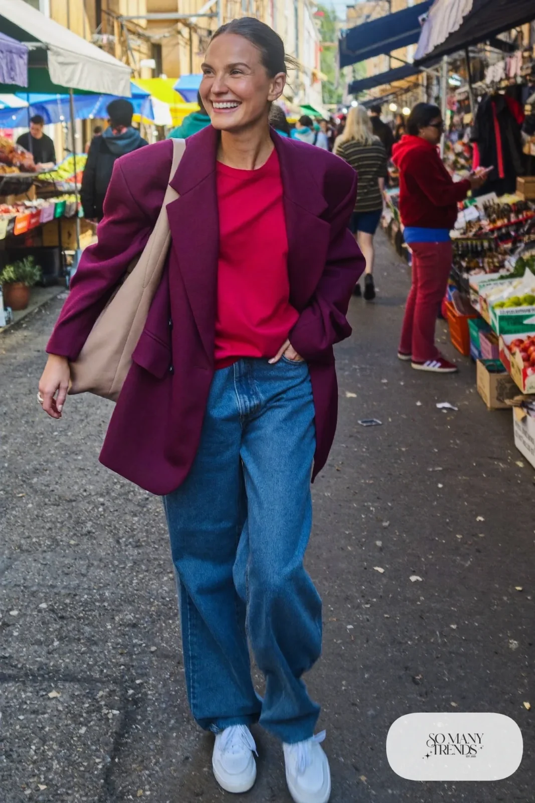 Woman in a plum oversized blazer, cherry red tee, wide-leg blue jeans and white sneakers, look 2