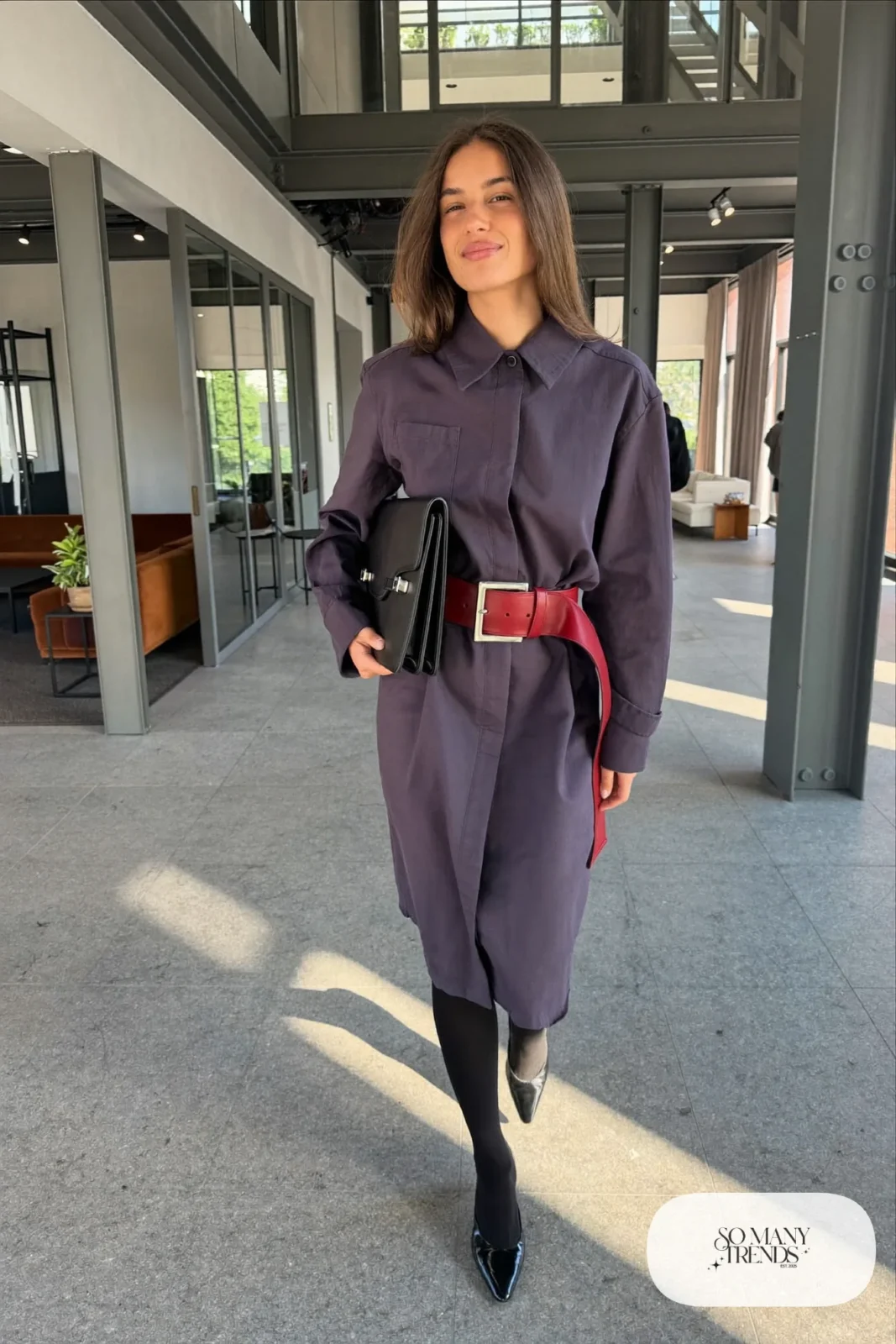 Woman in an eggplant midi shirt dress with a wide red belt and black pointed flats, look 25