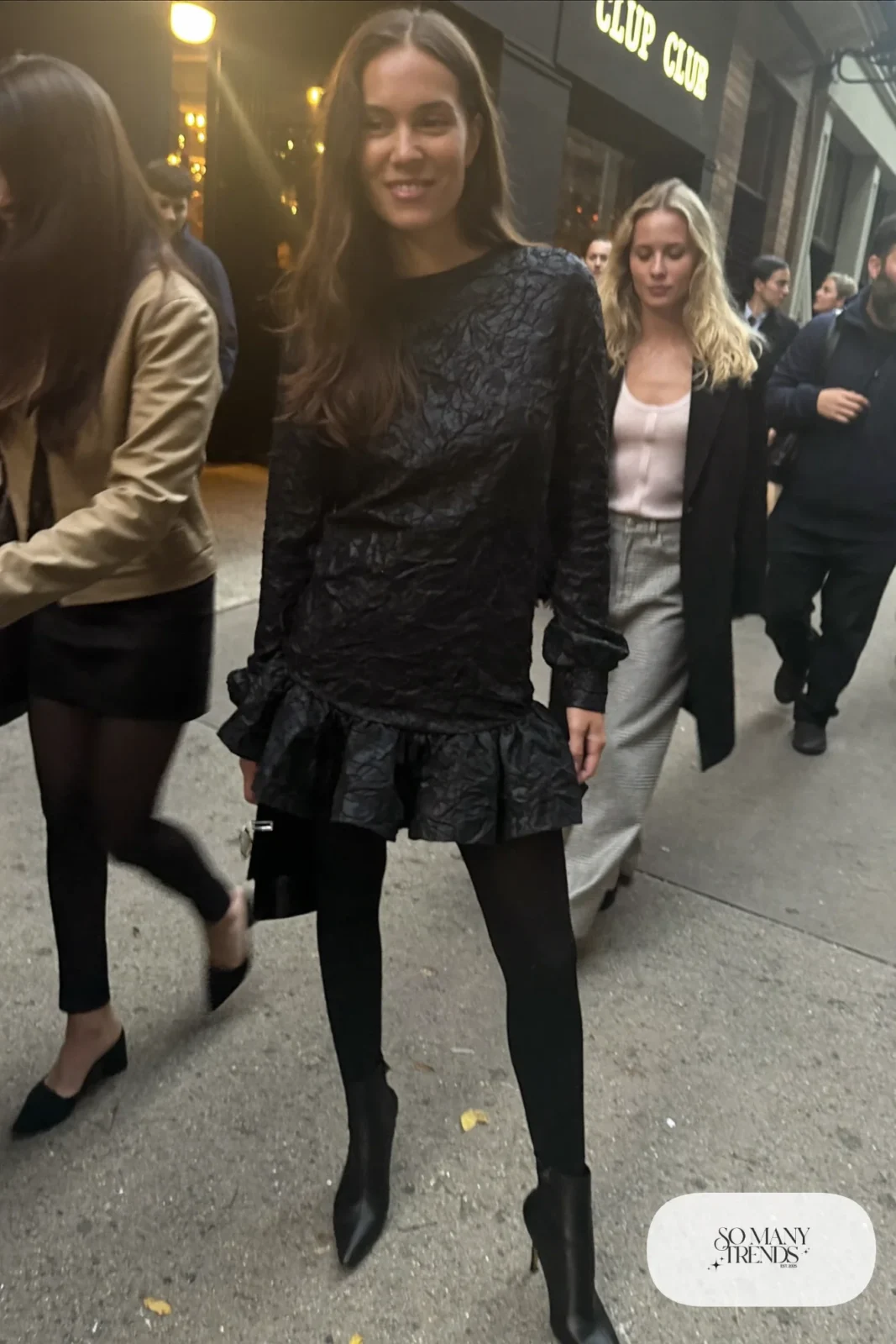 Black long-sleeve ruffle-hem mini dress with black opaque tights and black heeled ankle boots, outfit 29