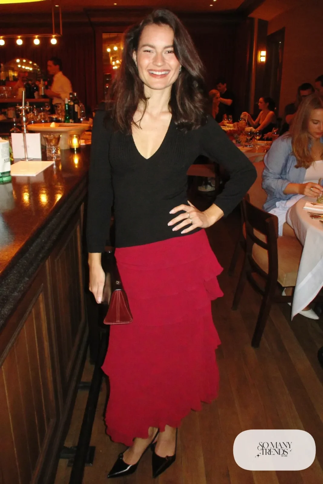 Wine red tiered midi skirt with fitted black V-neck knit top and black pointed pumps, outfit 10