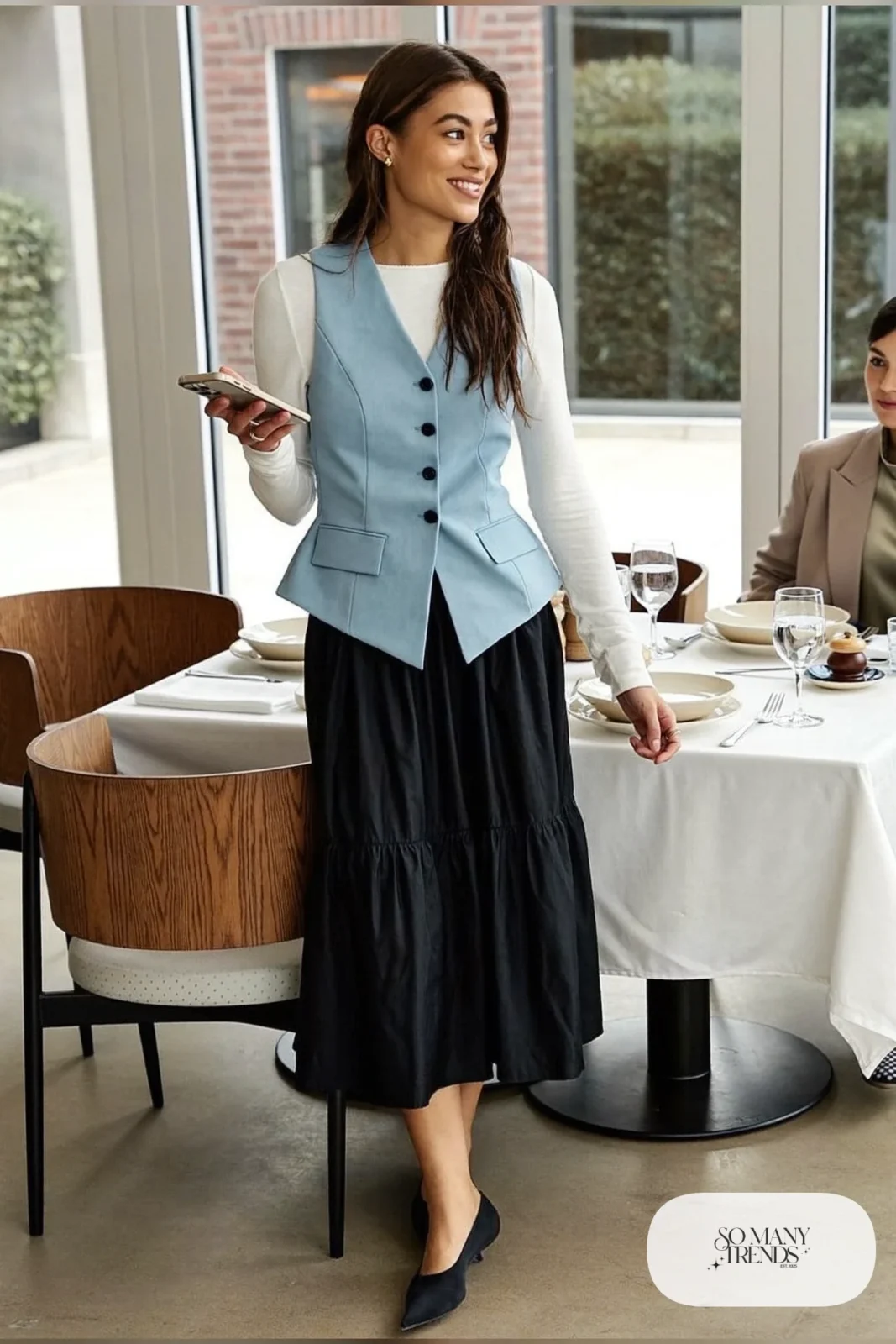 Black tiered midi skirt with powder blue tailored vest over fitted white top and black pointed flats, outfit 16