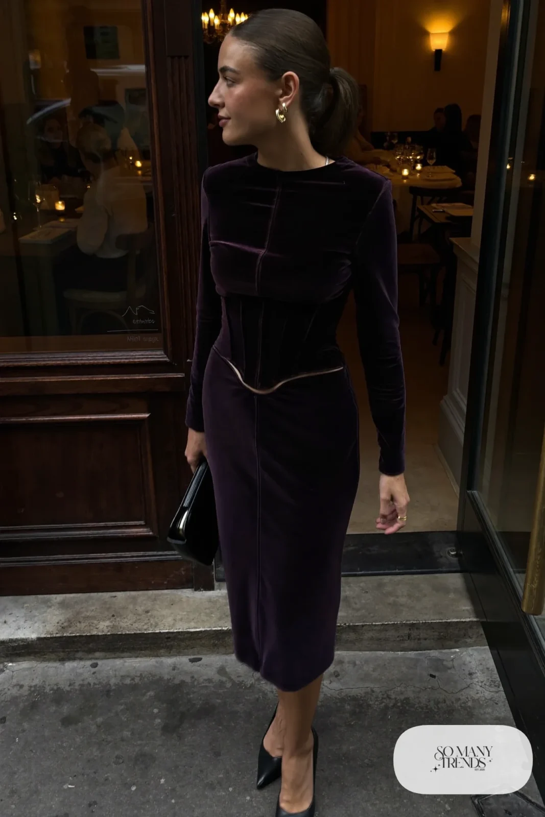 Woman in a plum velvet corset column dress with long sleeves and black pointed heels, outfit 17