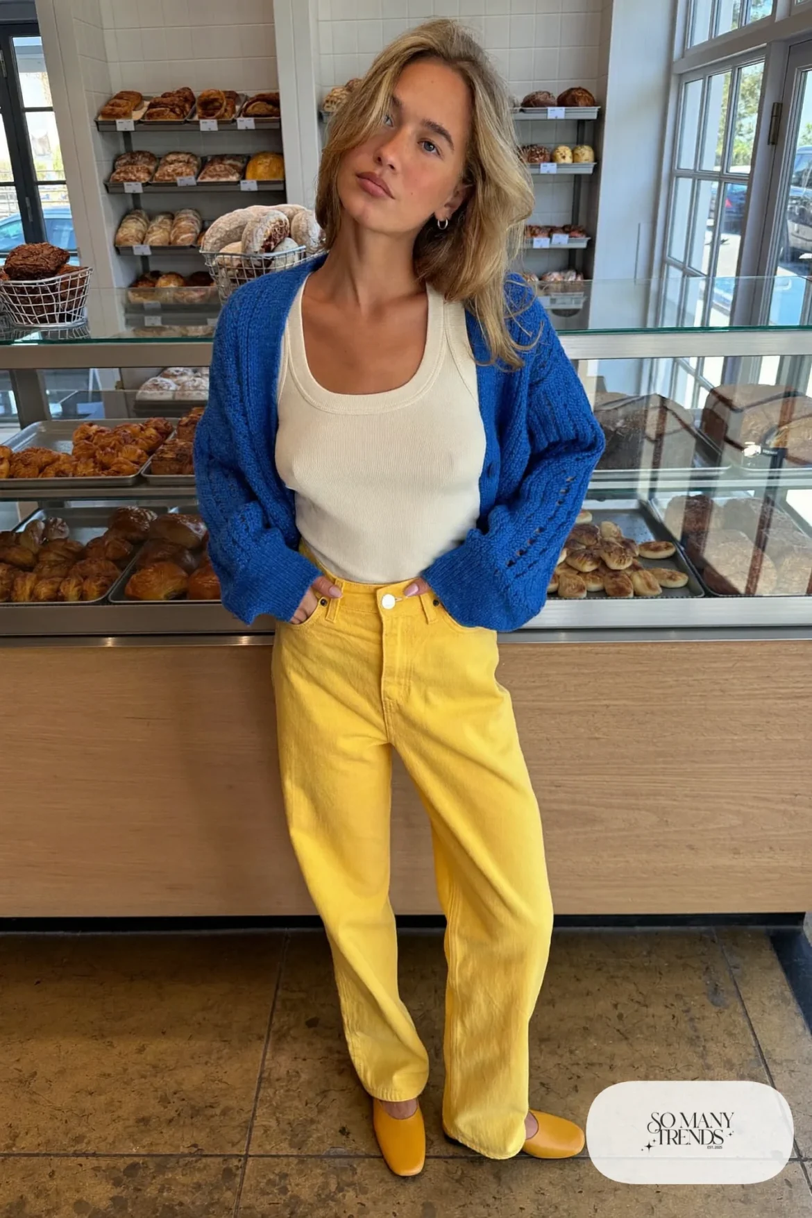 Open cobalt blue knit cardigan over a cream tank with high-waist mustard straight pants and tan flats, outfit 25