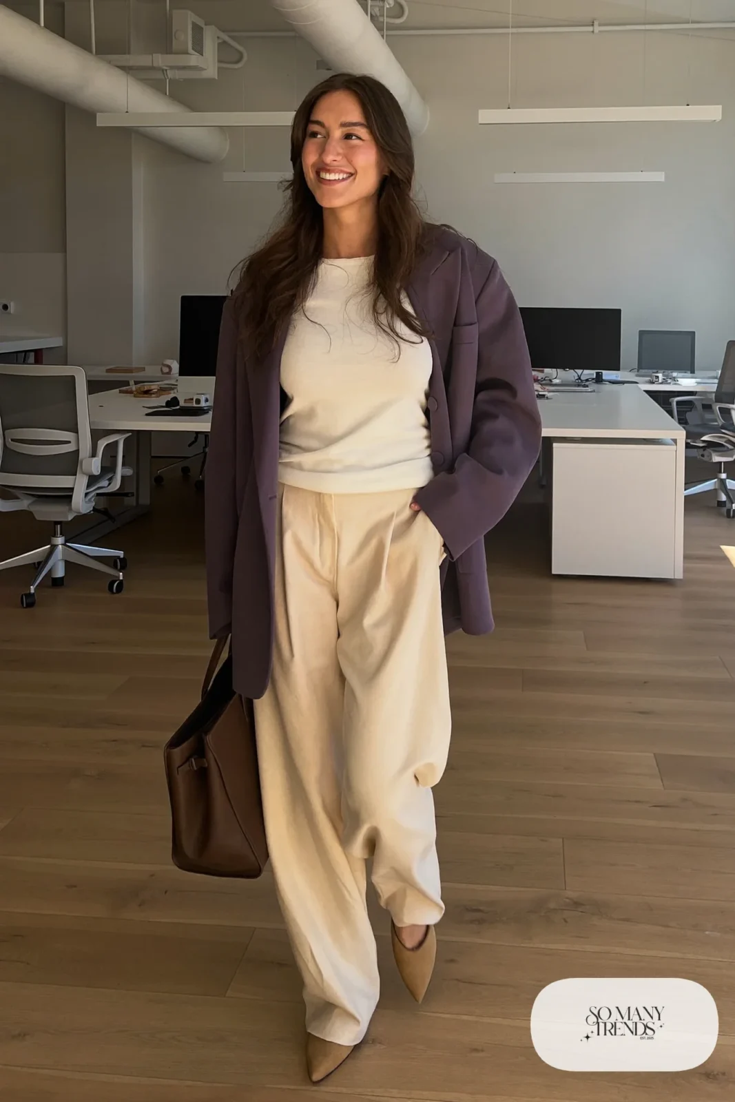 Woman in an oversized eggplant blazer, white fitted top, cream wide-leg pants and tan pointed flats in an office, outfit 1