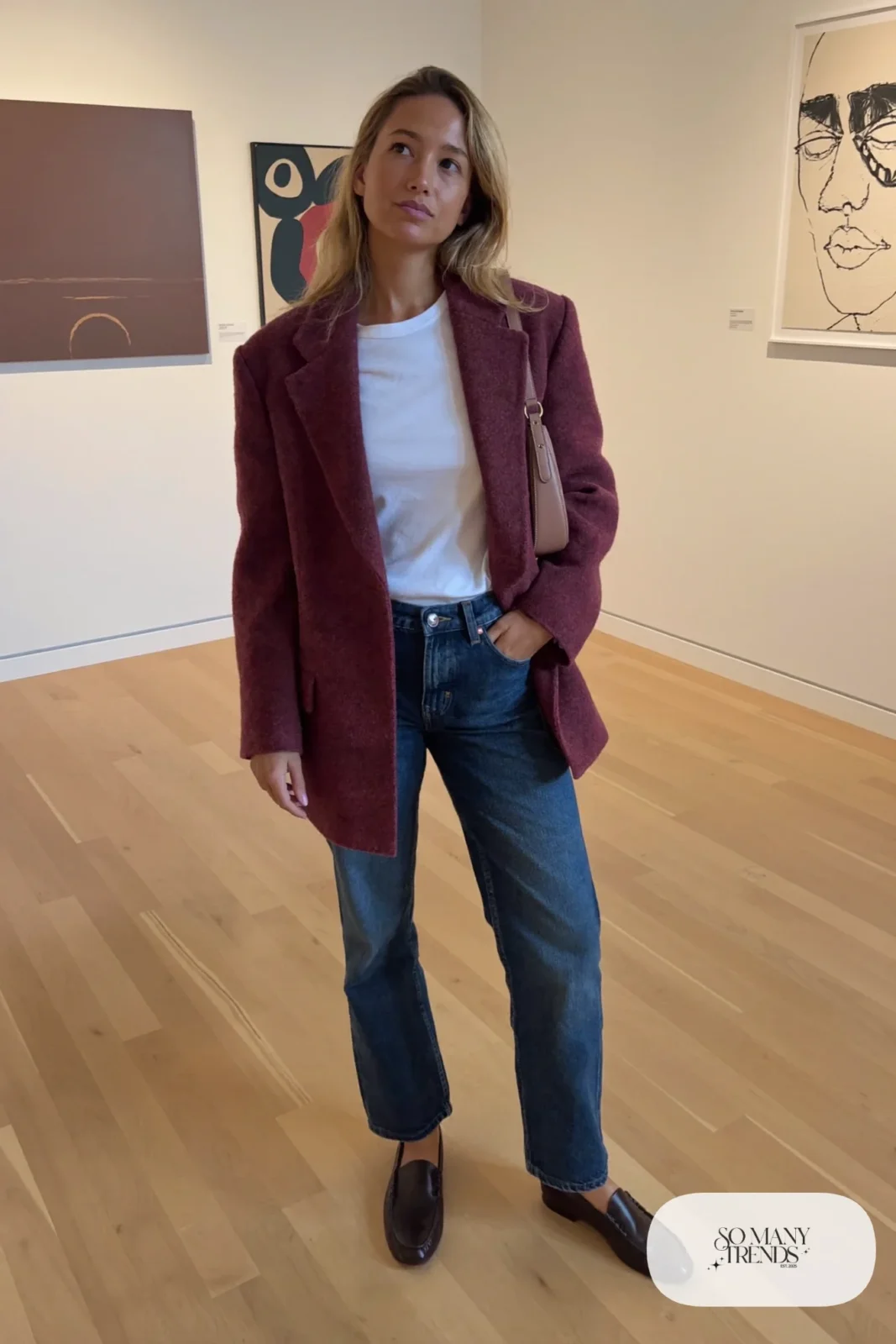 Woman in a plum wool blazer, white tee, straight dark jeans and brown loafers in a gallery, outfit 7