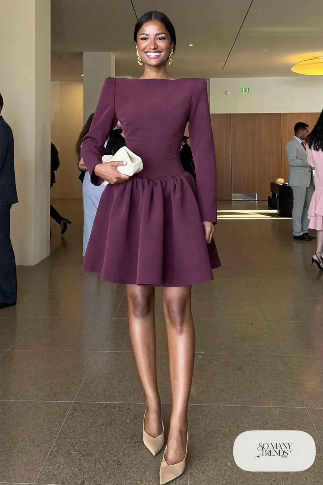 Woman in a plum structured cocktail dress, nude pointed pumps and gold earrings at an event lobby, outfit 19