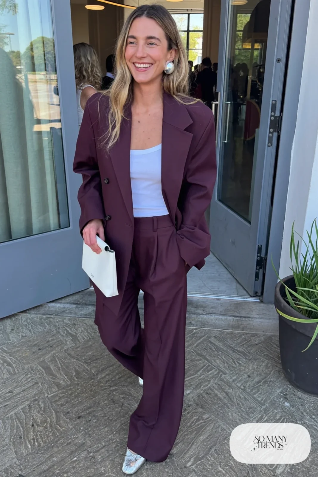 Woman in a plum wide-leg pantsuit, white tank and silver flats at an event venue, outfit 26
