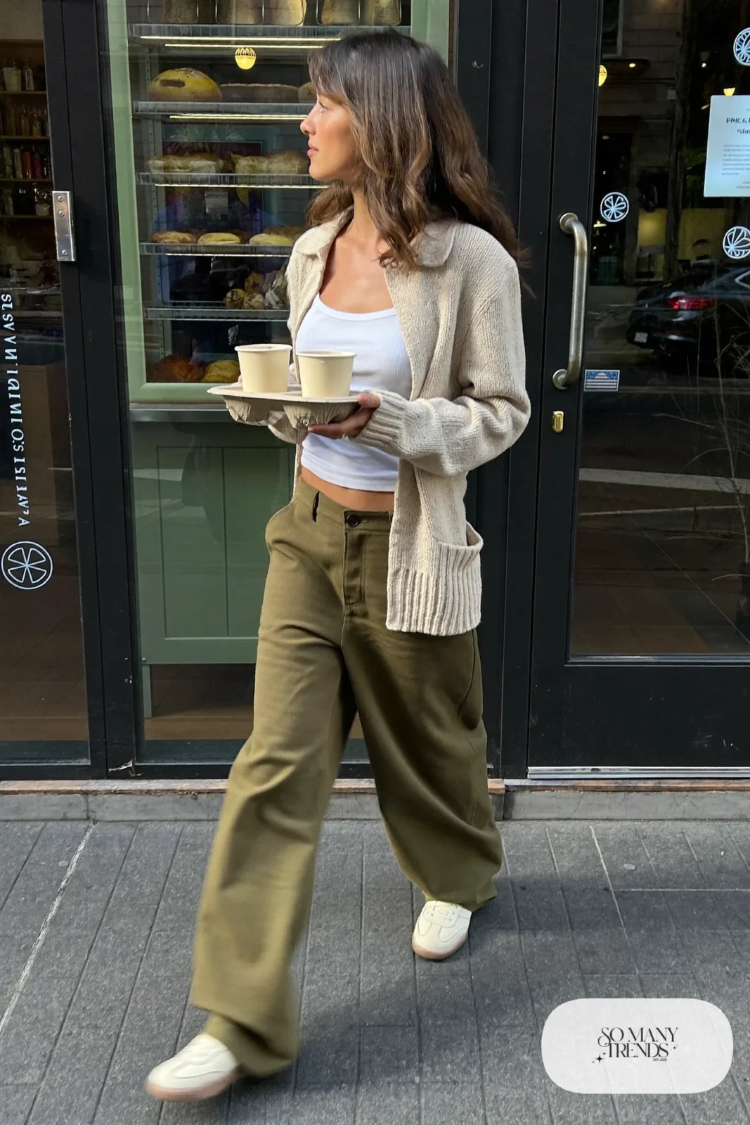Woman in an oatmeal short cardigan, white tank, barrel-leg olive pants and cream sneakers, outfit 4