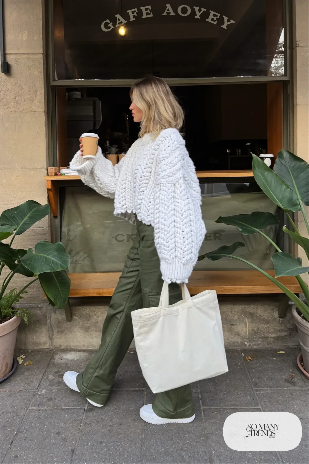 Woman in a white chunky sweater, olive cargo pants and white sneakers, outfit 14