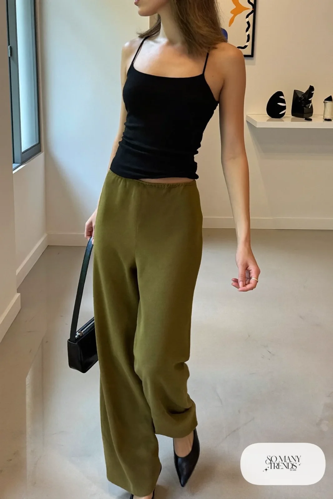 Woman in a black knit tank, matte olive trousers and black slingback pumps, outfit 21