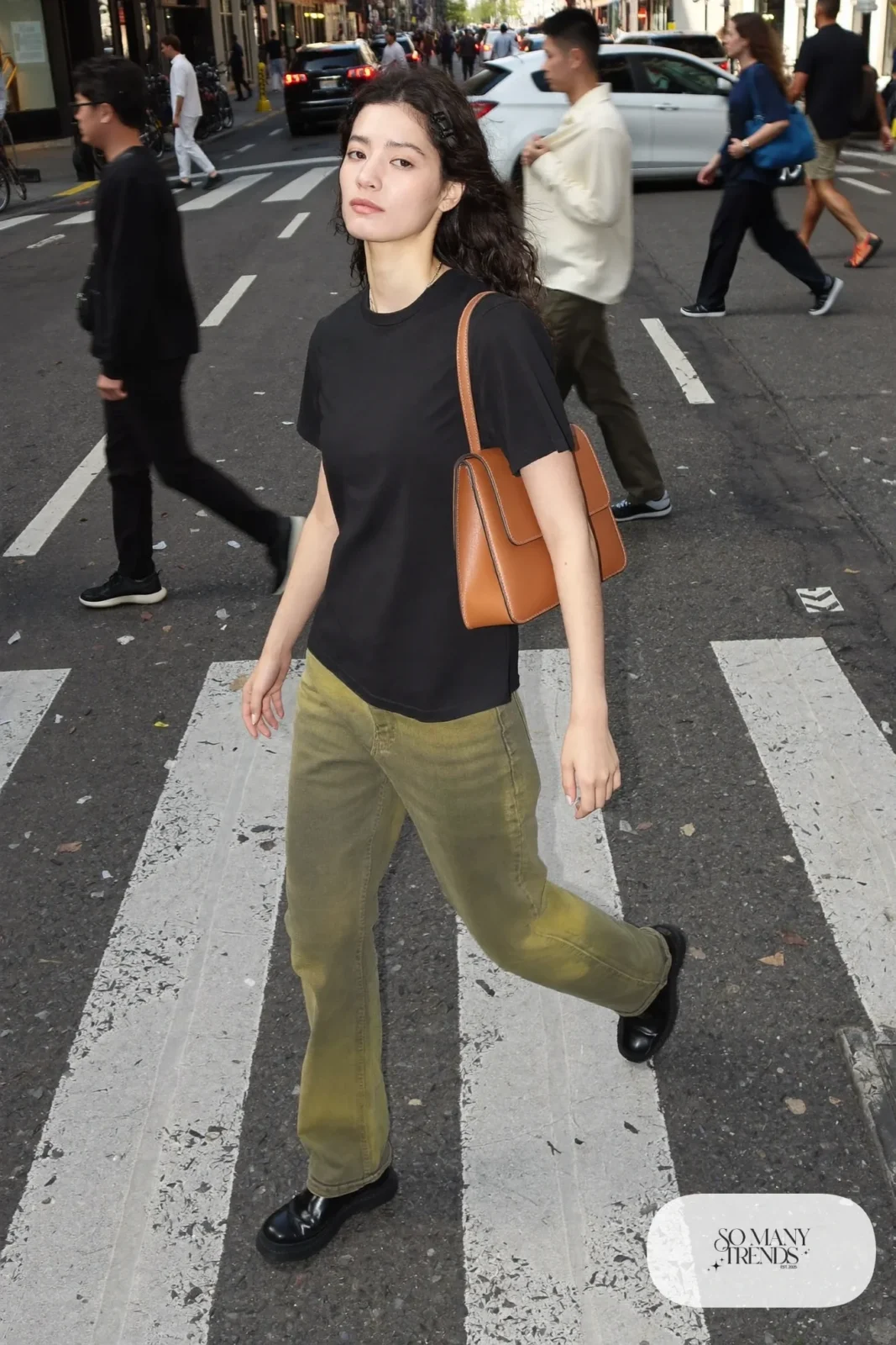 Woman in a black tee, olive pants, tan leather bag and black sneakers, outfit 28