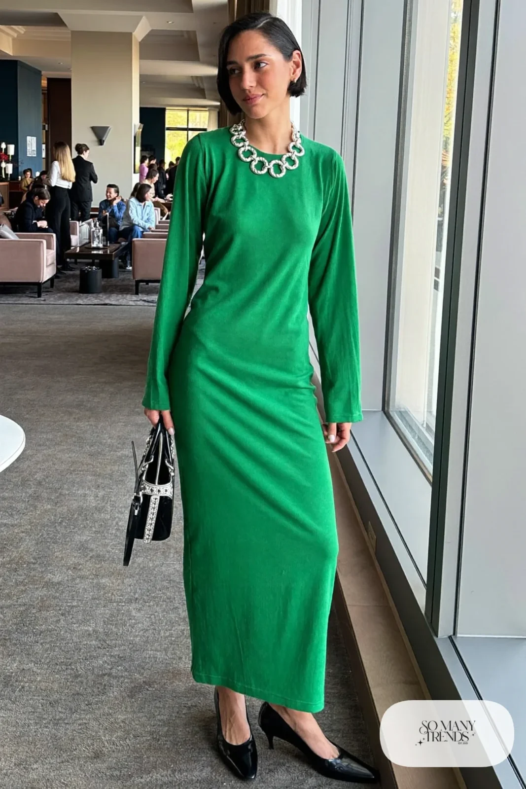 Woman in a forest green crew neck column dress with a thick silver chain necklace and low pumps, outfit 5
