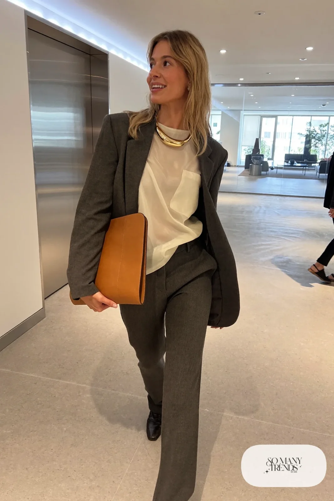 Woman in a charcoal relaxed blazer over a cream shell with a sculptural collar necklace and straight pants, outfit 6
