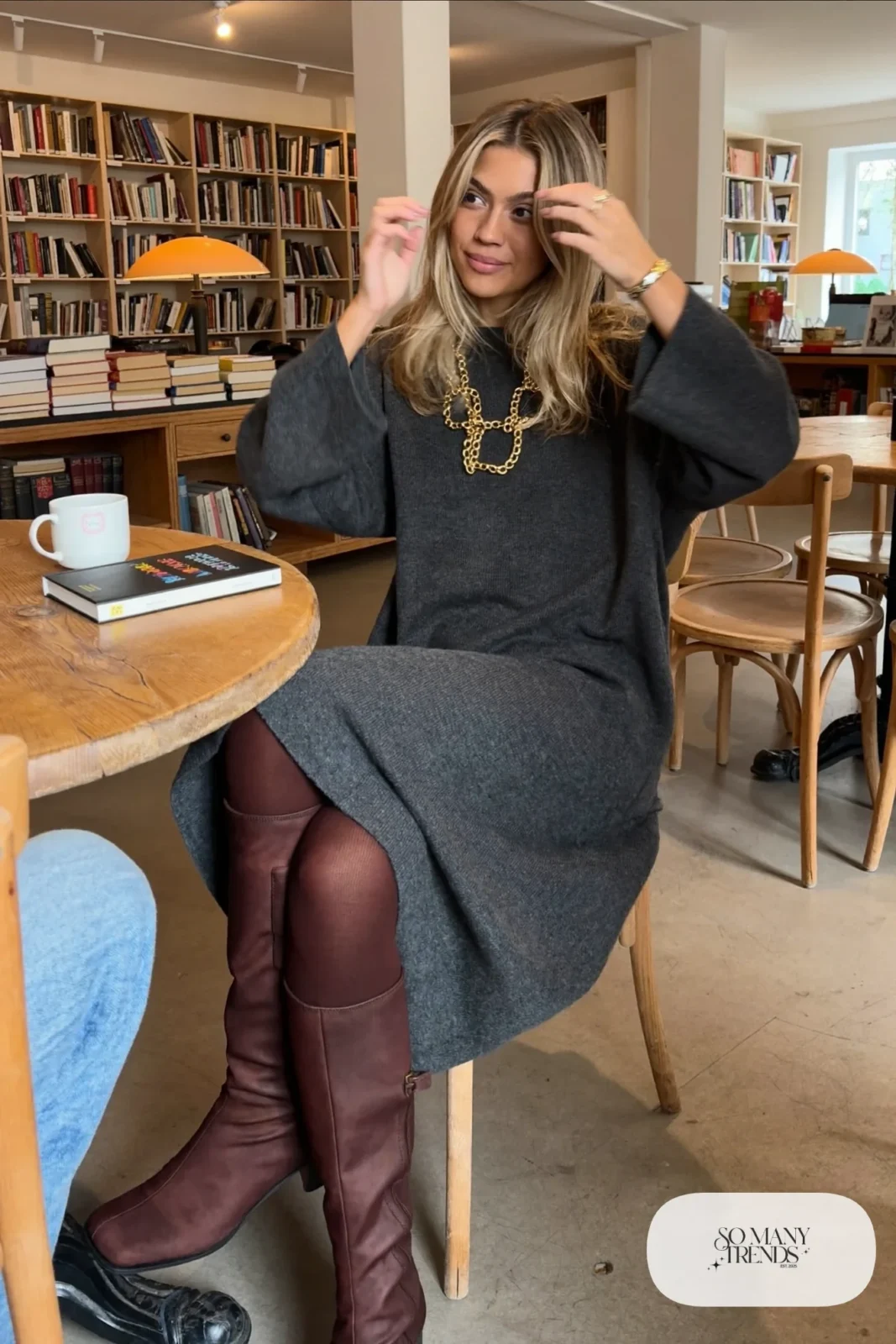 Woman in a loose charcoal knit maxi dress with a bold link chain necklace, tights and brown boots, outfit 12
