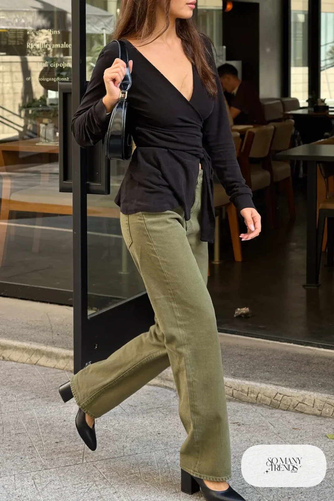 Woman in a black wrap-front knit top, straight olive pants and black block heels, outfit 23