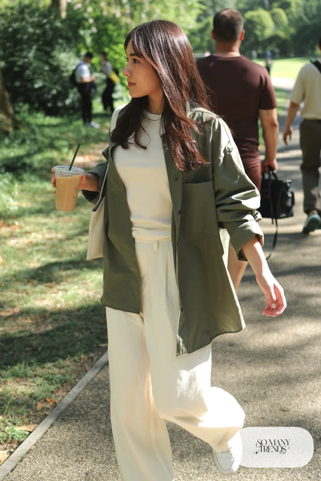 Woman in an open olive overshirt, cream tee, cream wide-leg pants and white sneakers, outfit 27