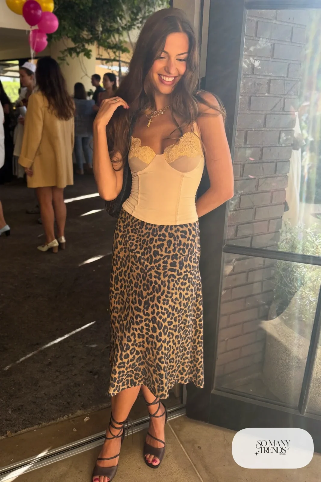 Woman in an ecru lace-trim fitted top, leopard print bias midi skirt and chocolate brown strappy closed-toe heels, outfit 18