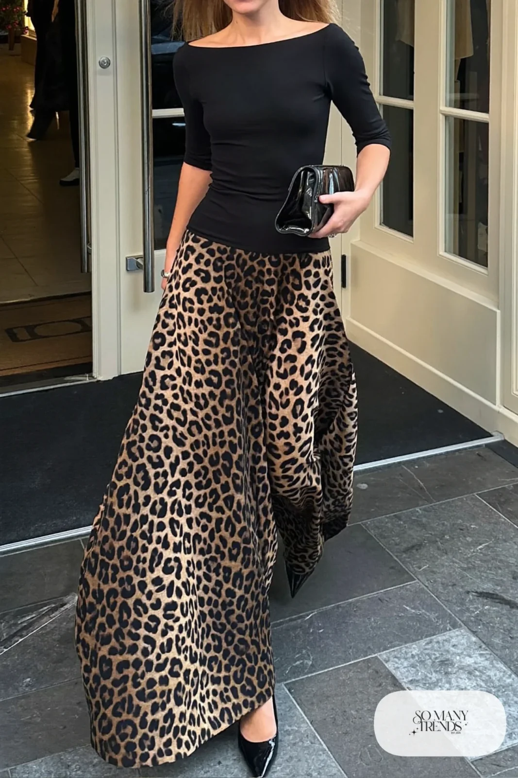 Woman in a black fitted boat-neck top, floor-length leopard print full skirt and black pointed heels with a clutch, outfit 25