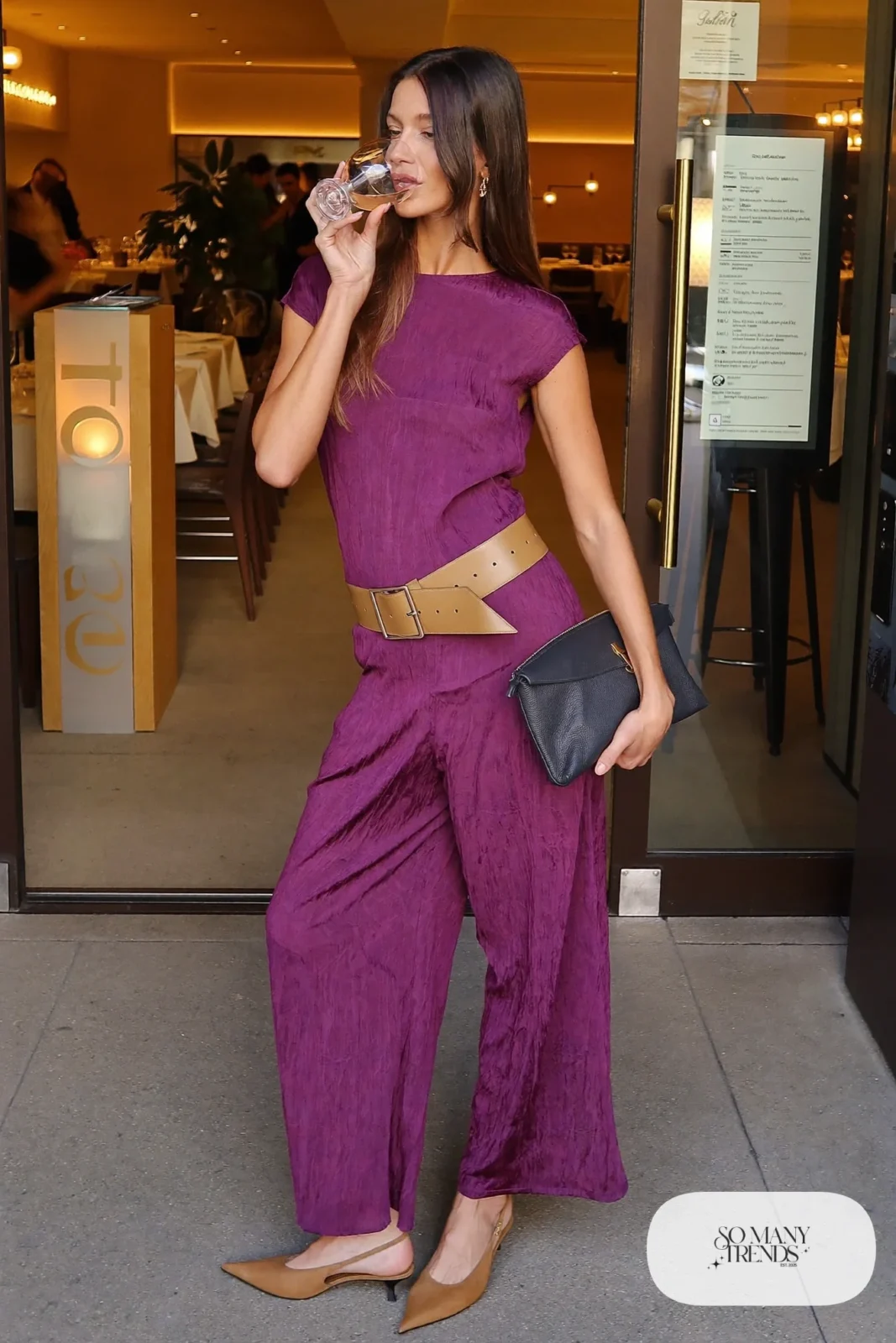 Woman in a wide-leg eggplant jumpsuit with a tan belt and tan slingback heels at a dinner venue, outfit 5