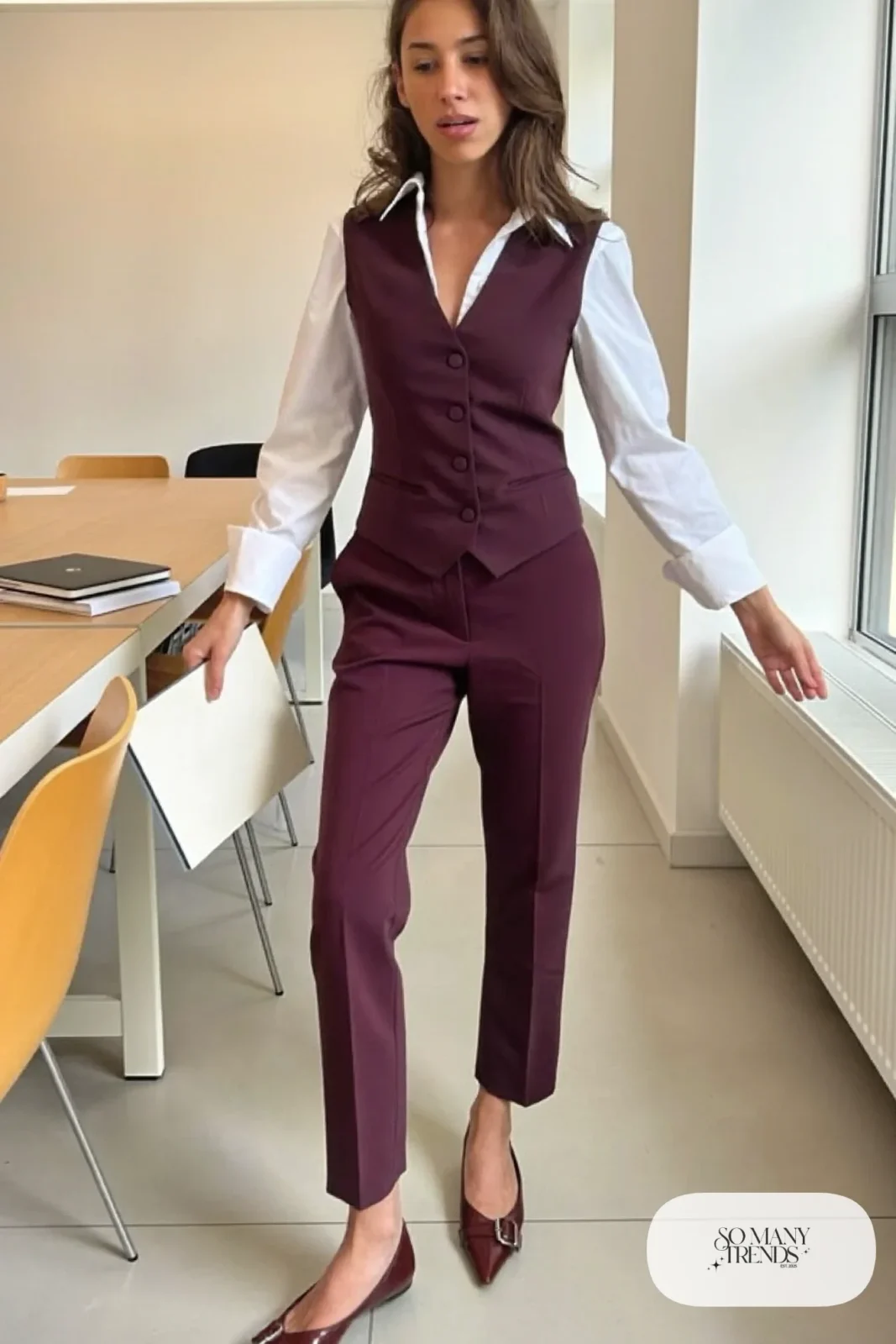 Woman in a plum tailored vest and straight pants set with white shirt and brown pointed flats in a meeting room, outfit 12