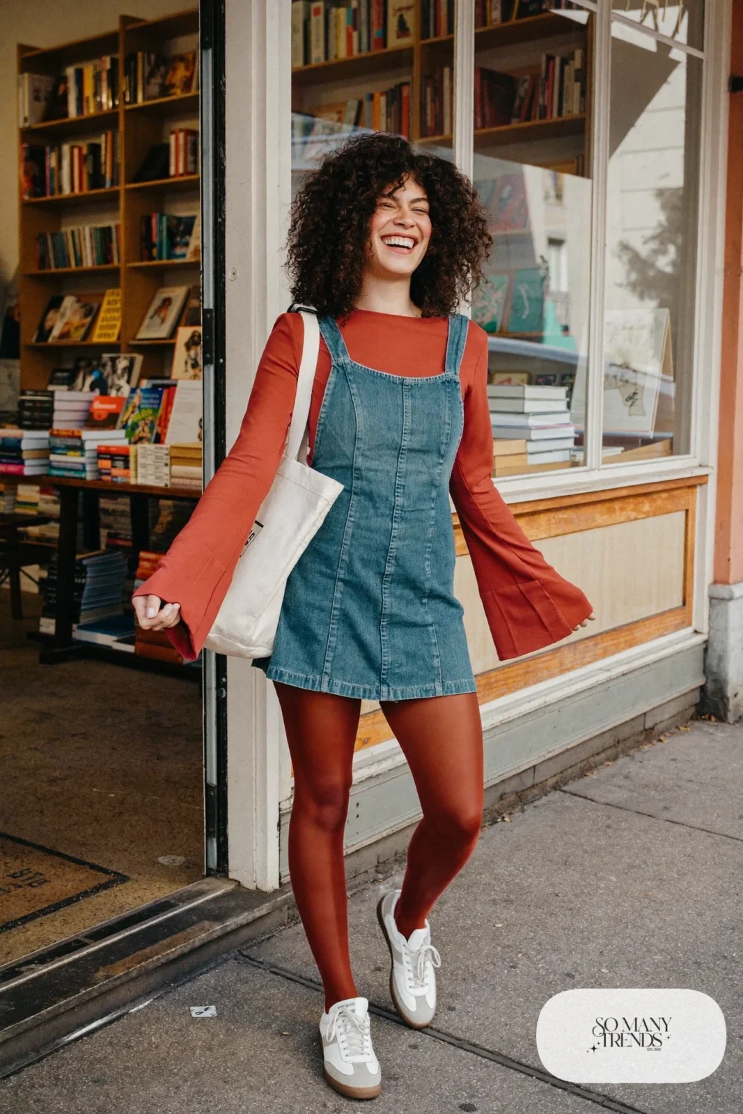 Look 6: terracotta bell sleeve top under a mid-wash denim pinafore dress with white leather sneakers