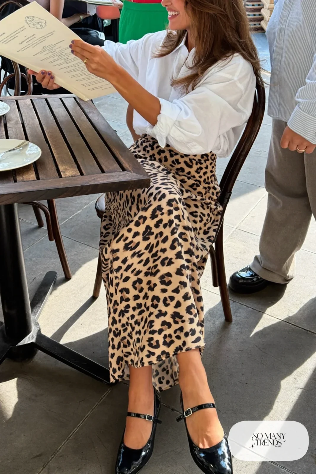 Woman in a white cotton poplin shirt, leopard print bias midi skirt and black patent Mary Jane shoes, outfit 4
