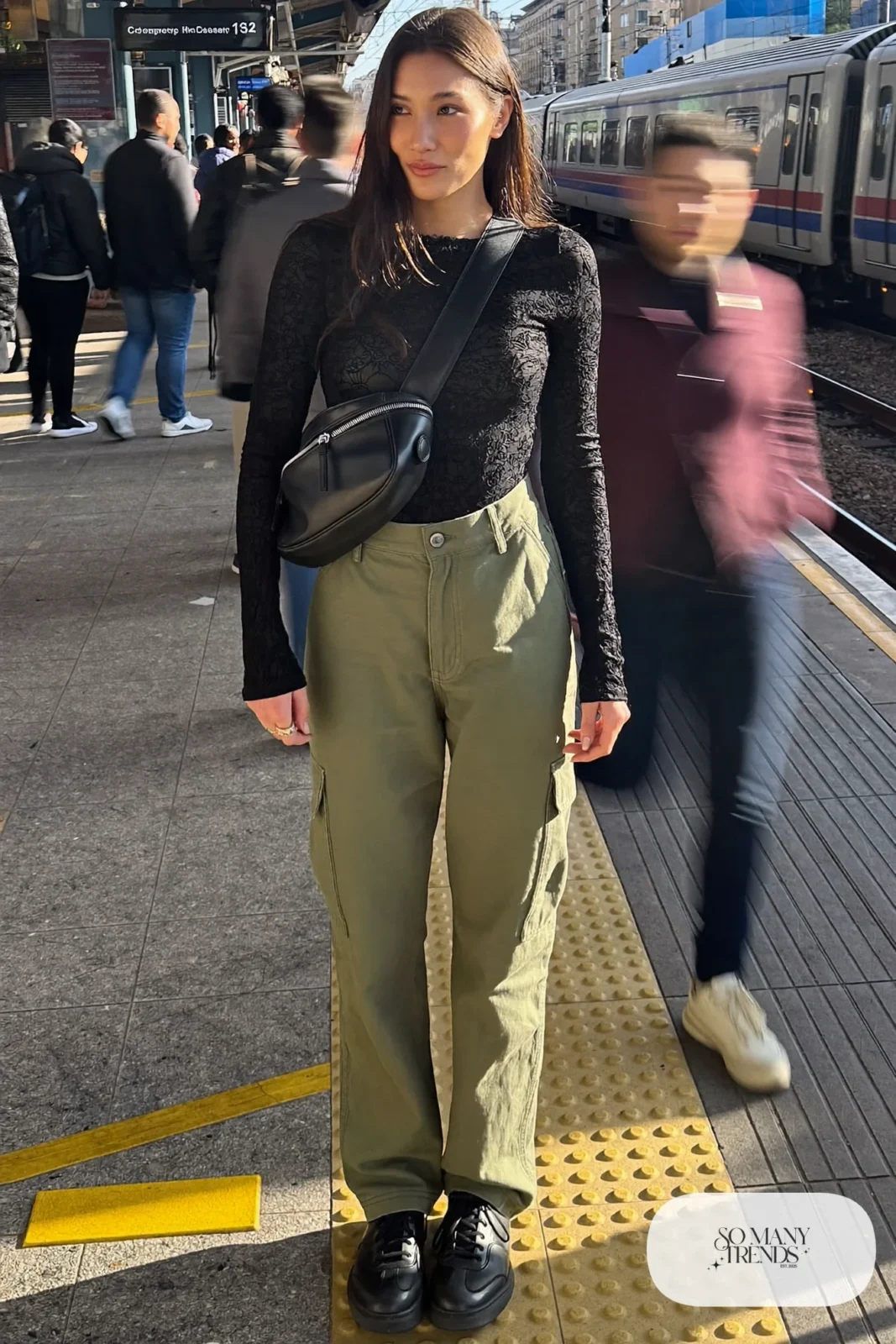 Black long-sleeve lace top with olive green relaxed cargo pants, black leather sneakers and a black crossbody bag, look 10