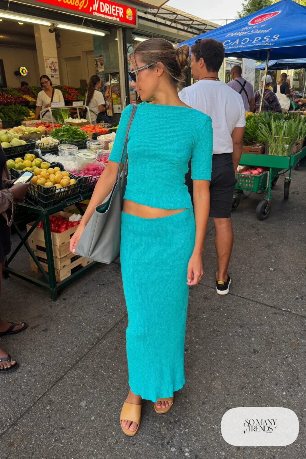 Woman in a turquoise knit top and long skirt set with tan flats and a gray tote, outfit 18
