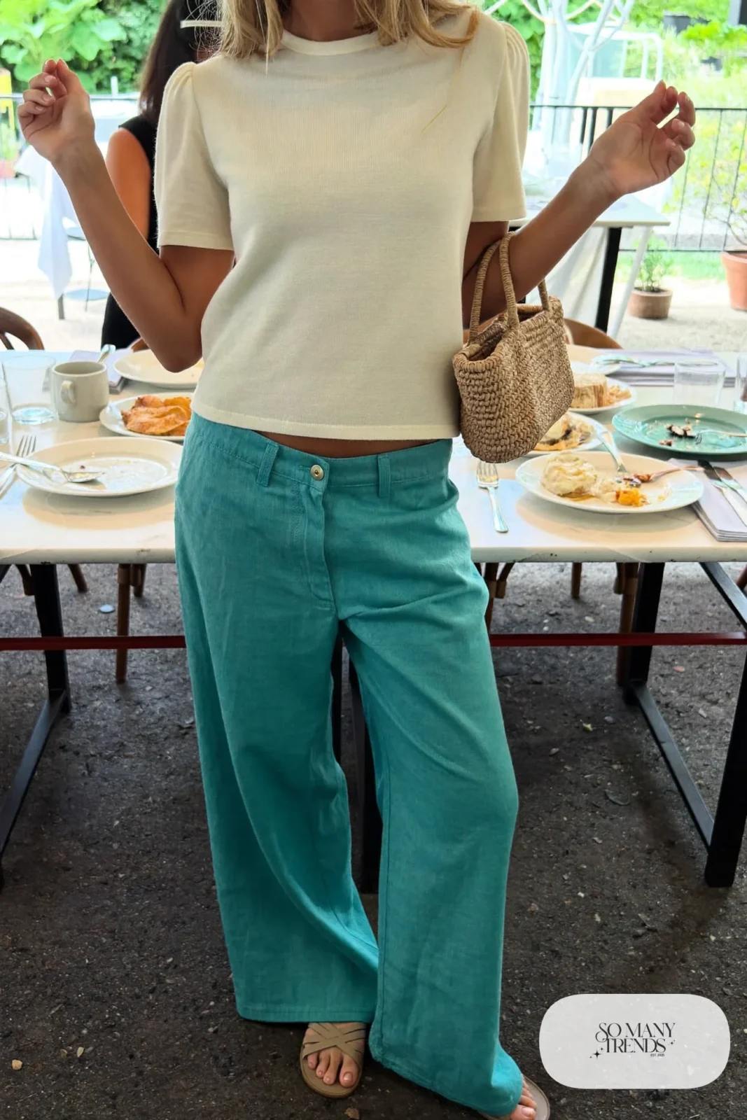 Woman in turquoise wide-leg linen pants, cream knit top and tan flat sandals, outfit 24