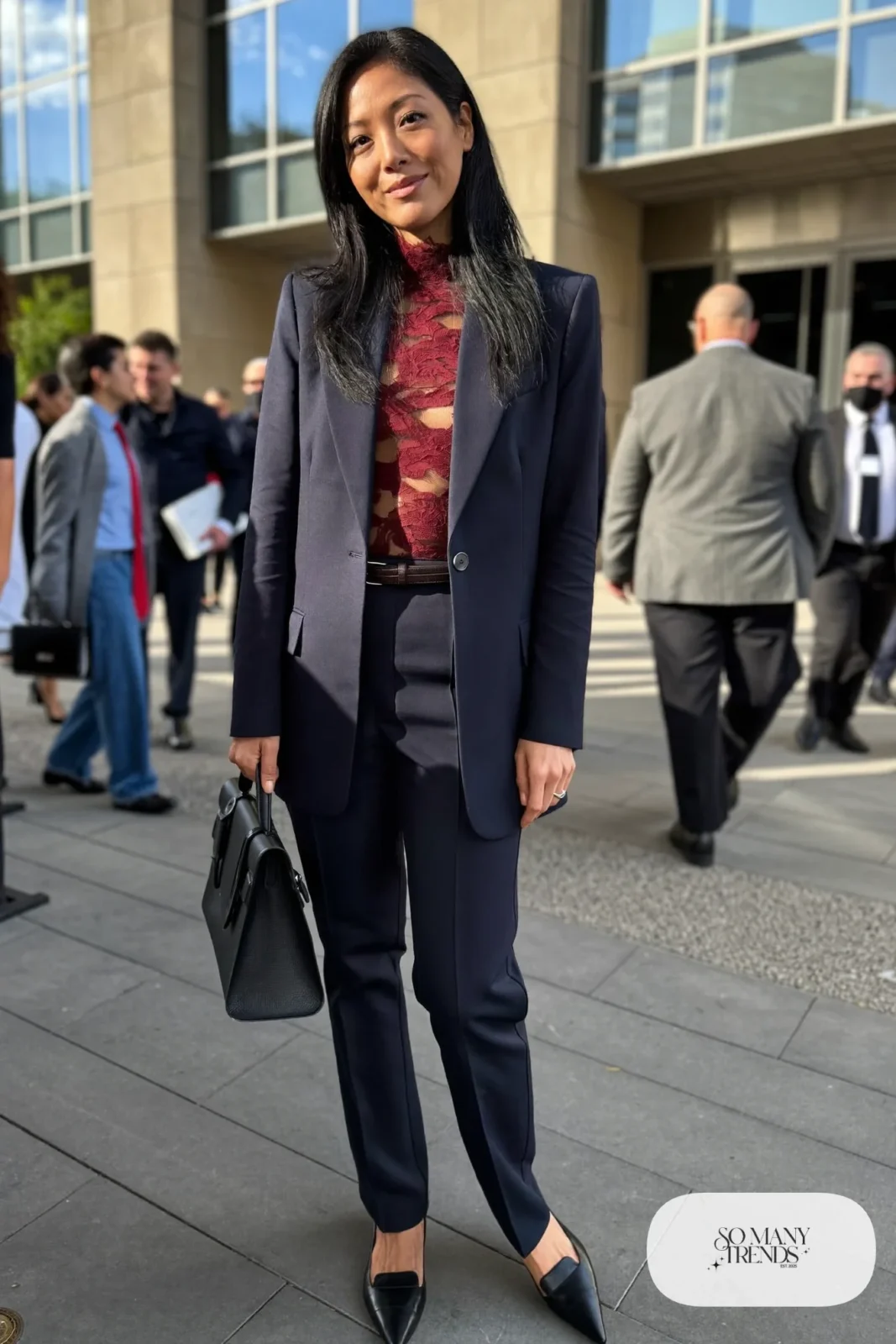 Burgundy long-sleeve lace top under a tailored navy blazer with navy trousers and black pointed flats, look 20