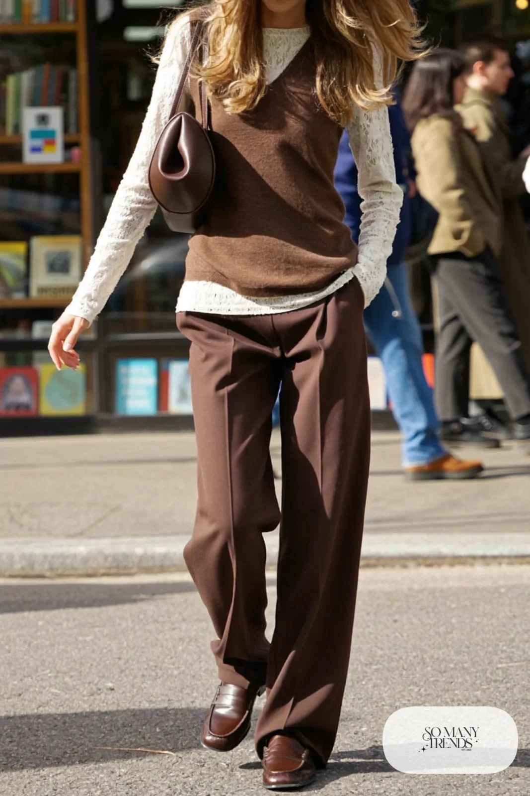 Ivory long-sleeve lace top under a chocolate brown knit vest with dark brown wide-leg pants and brown loafers, look 22