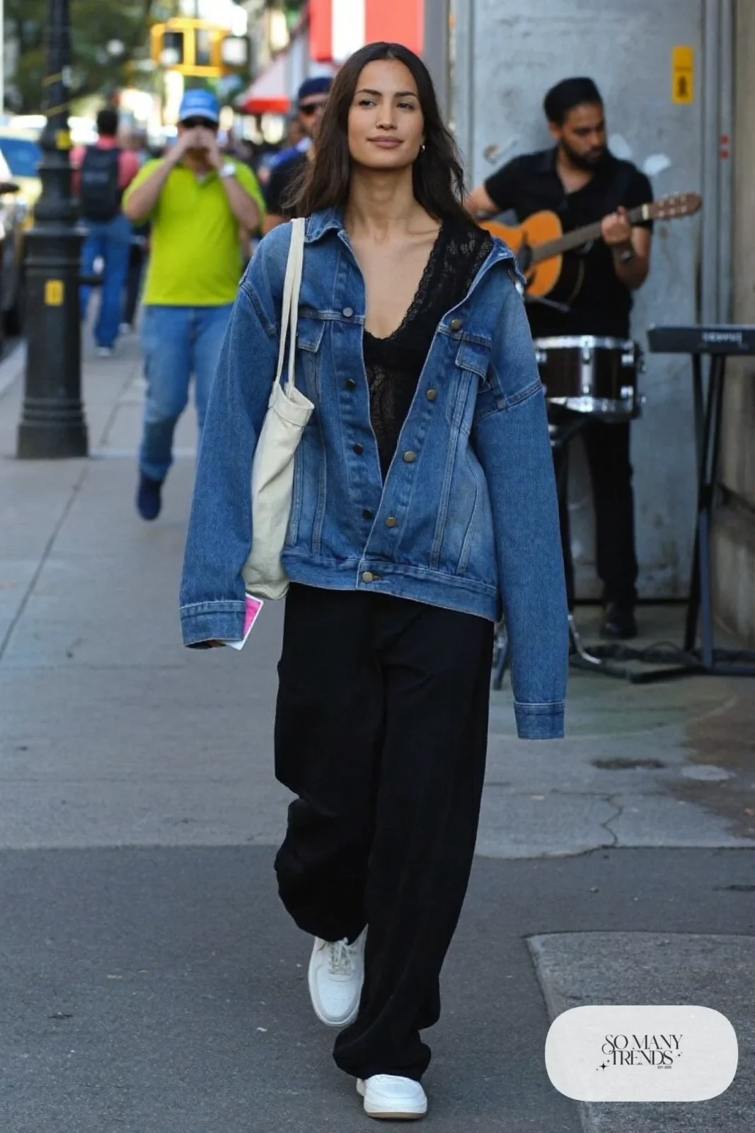 Black long-sleeve lace top under an oversized washed denim jacket with black wide-leg pants and white sneakers, look 23