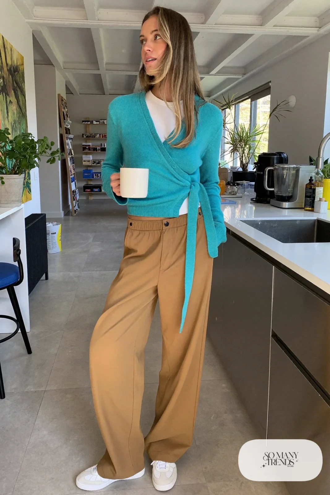 Woman in a turquoise wrap cardigan, white tee, tan wide-leg pants and white sneakers, outfit 4