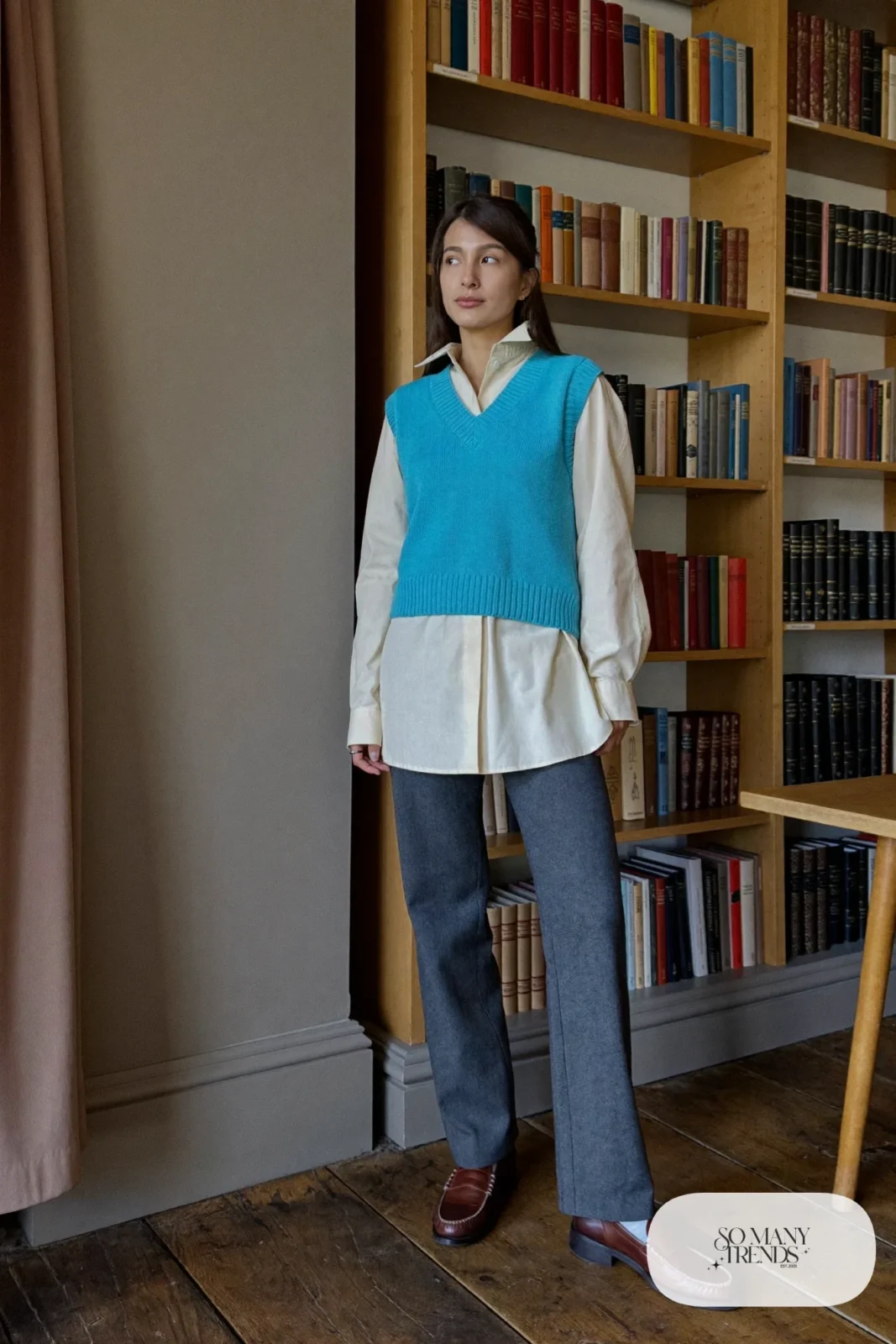 Woman in a turquoise knit vest, cream blouse, gray straight pants and brown loafers, outfit 12