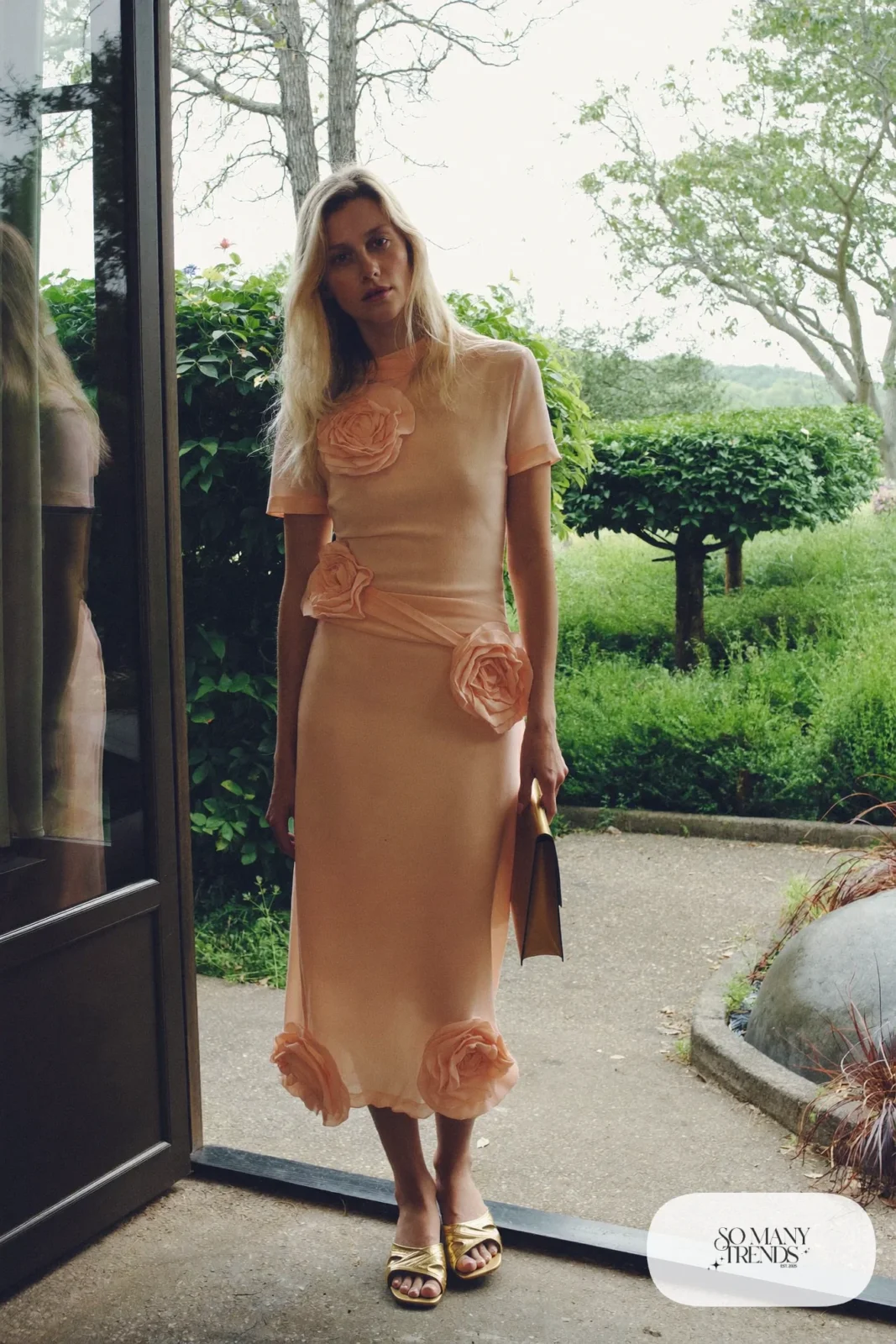 Woman in a soft peach midi dress with 3D flower appliqué and flat gold-toned sandals at a shower, garden party outfit 9