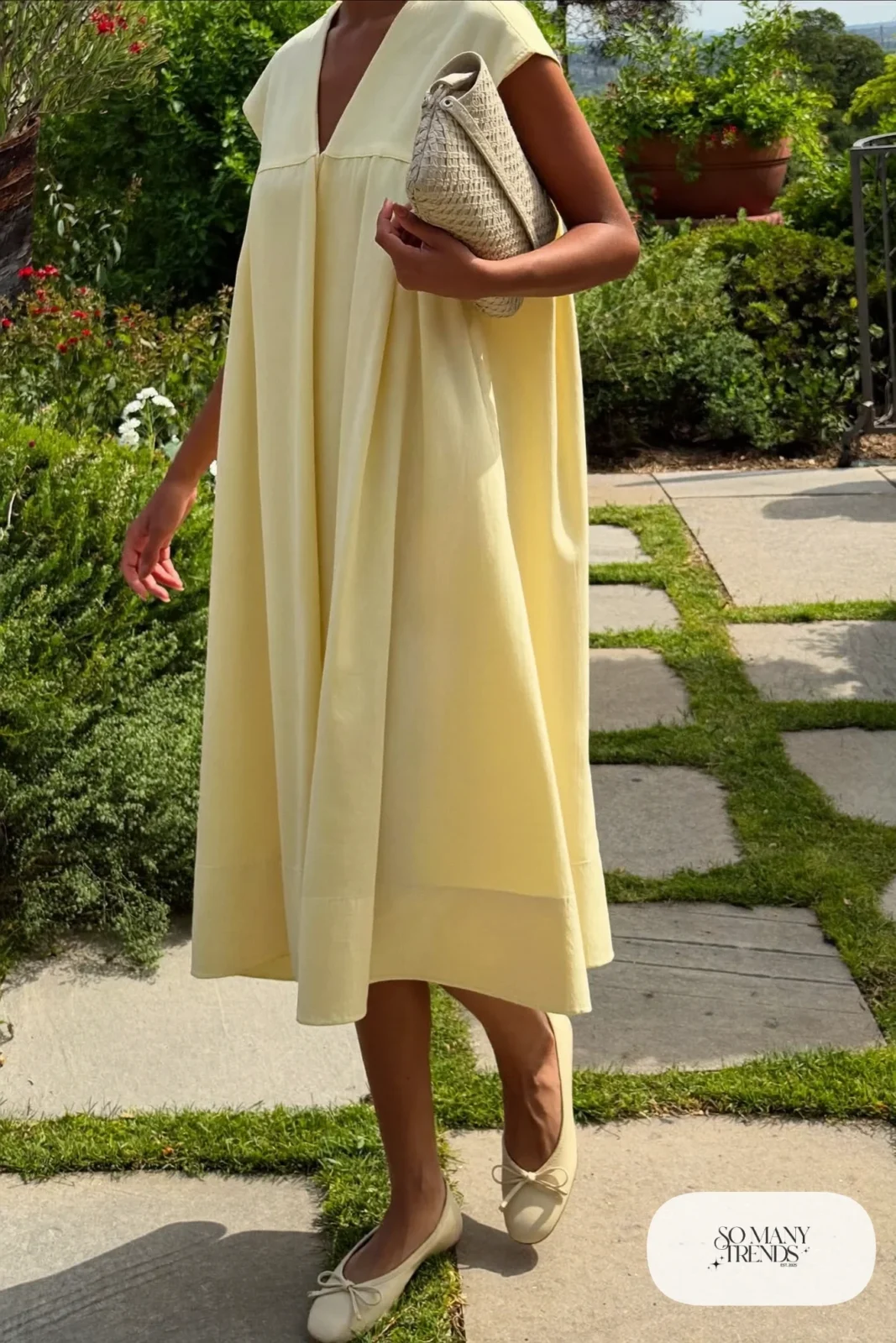 Woman in a butter yellow crepe midi dress with cream bow flats at a garden lunch, garden party outfit 3
